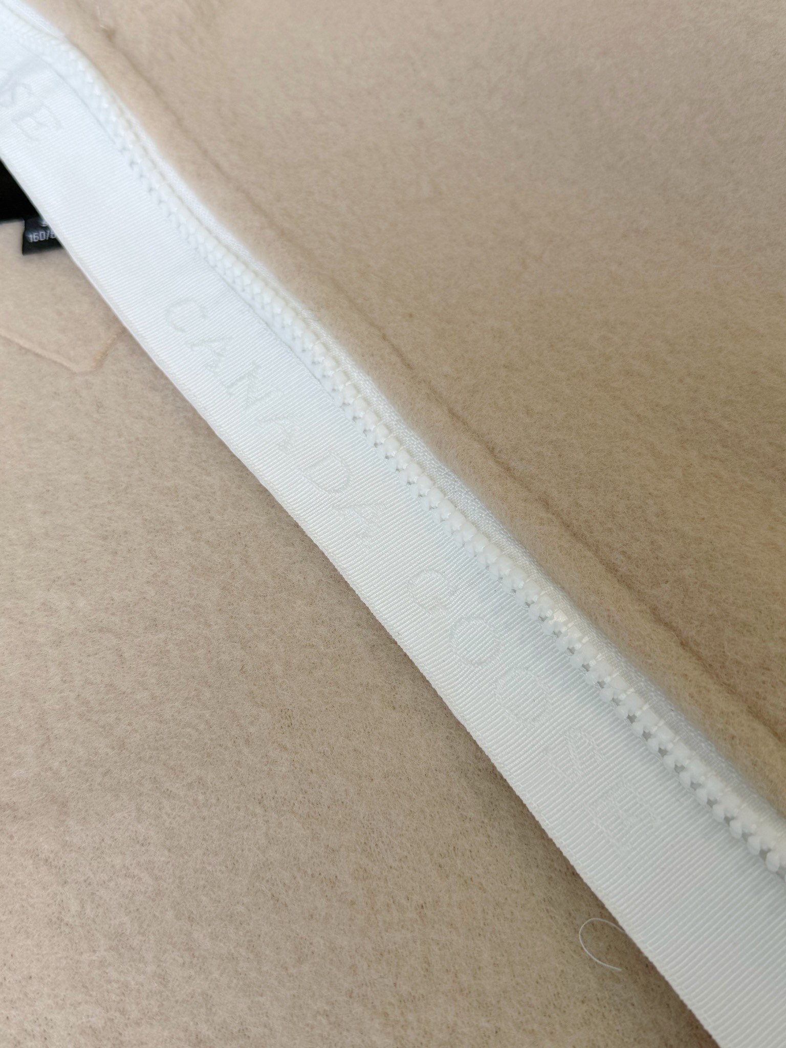 大鹅/Canada Goose抓绒羊毛饰章连帽夹克外套 面料选择: 以羊毛为主体，加入极少量氨纶和聚酯纤维混纺而成的羊毛抓绒面料。羊毛作为核心天然成分，提供无与伦比的温度调节、抑菌防臭和亲肤感。少量氨纶的喂入赋予了面料一定的四向弹性，日常活动时毫无束缚感。作为抓绒结构的基础，聚酯纤维增强了面料的耐久性、抗皱性和快干性，它构成了抓绒的蓬松感，并提供锁住空气等功能。 细节1: 衣袖和下摆采用2乘2罗纹收口，其强大的弹性，可以紧密贴合不同粗细的手腕和腰部，形成一个有效的&lsquo;密封&rsquo;,防止冷风倒灌。在多次拉伸和使用后仍能保持原有形状，不易松垮变形。且罗纹袖口能传递一种设计感，强化视觉美观度。 细节2: 兜帽设计与松紧扣的搭配提升穿戴时的保暖度与防风性能。 辅料:定制弹性抽绳松紧扣定制拉链吊坠定制臂章 尺码：S M L 颜色：黑 灰 咖 米 粉