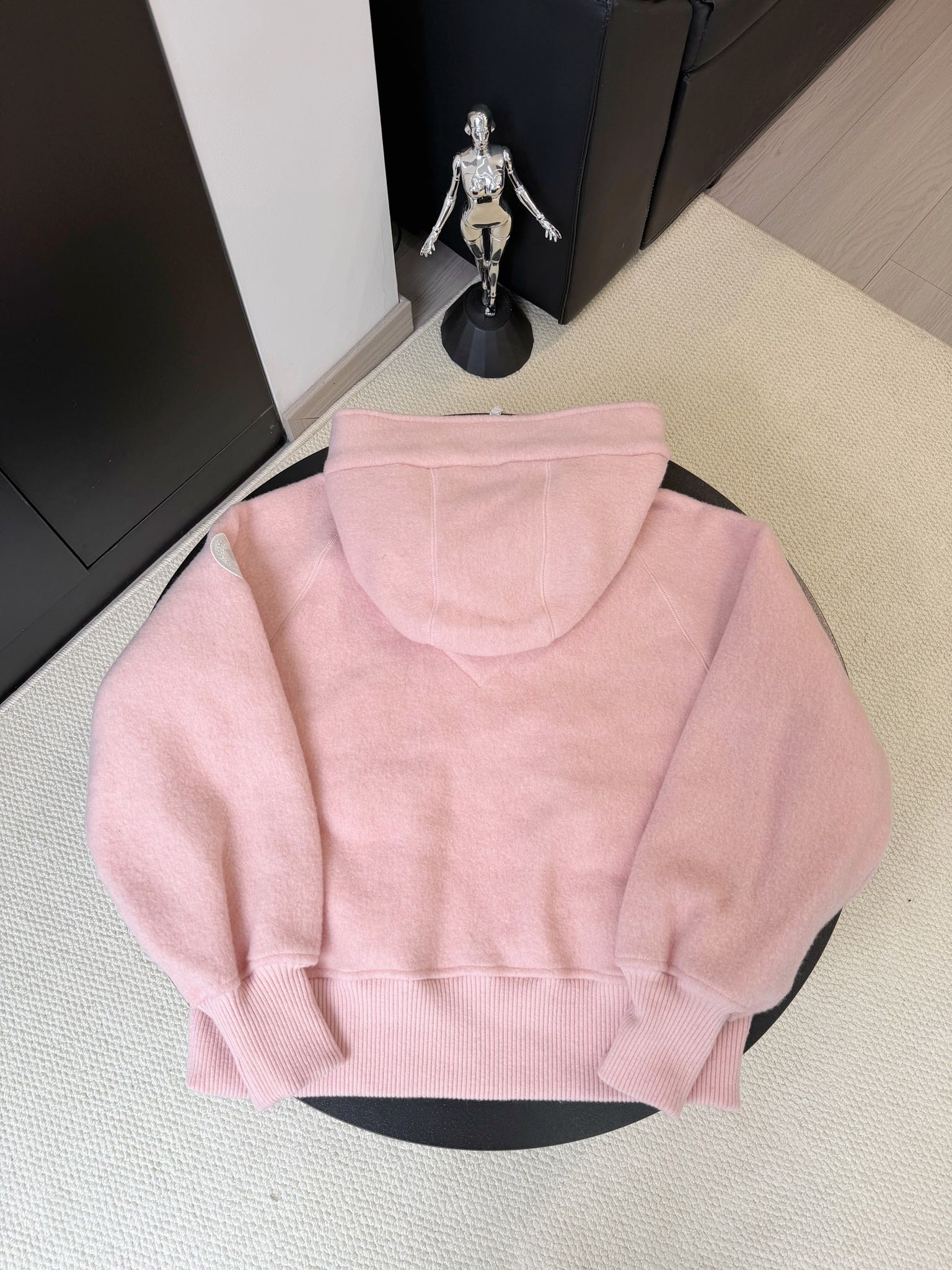 大鹅/Canada Goose抓绒羊毛饰章连帽夹克外套 面料选择: 以羊毛为主体，加入极少量氨纶和聚酯纤维混纺而成的羊毛抓绒面料。羊毛作为核心天然成分，提供无与伦比的温度调节、抑菌防臭和亲肤感。少量氨纶的喂入赋予了面料一定的四向弹性，日常活动时毫无束缚感。作为抓绒结构的基础，聚酯纤维增强了面料的耐久性、抗皱性和快干性，它构成了抓绒的蓬松感，并提供锁住空气等功能。 细节1: 衣袖和下摆采用2乘2罗纹收口，其强大的弹性，可以紧密贴合不同粗细的手腕和腰部，形成一个有效的&lsquo;密封&rsquo;,防止冷风倒灌。在多次拉伸和使用后仍能保持原有形状，不易松垮变形。且罗纹袖口能传递一种设计感，强化视觉美观度。 细节2: 兜帽设计与松紧扣的搭配提升穿戴时的保暖度与防风性能。 辅料:定制弹性抽绳松紧扣定制拉链吊坠定制臂章 尺码：S M L 颜色：黑 灰 咖 米 粉