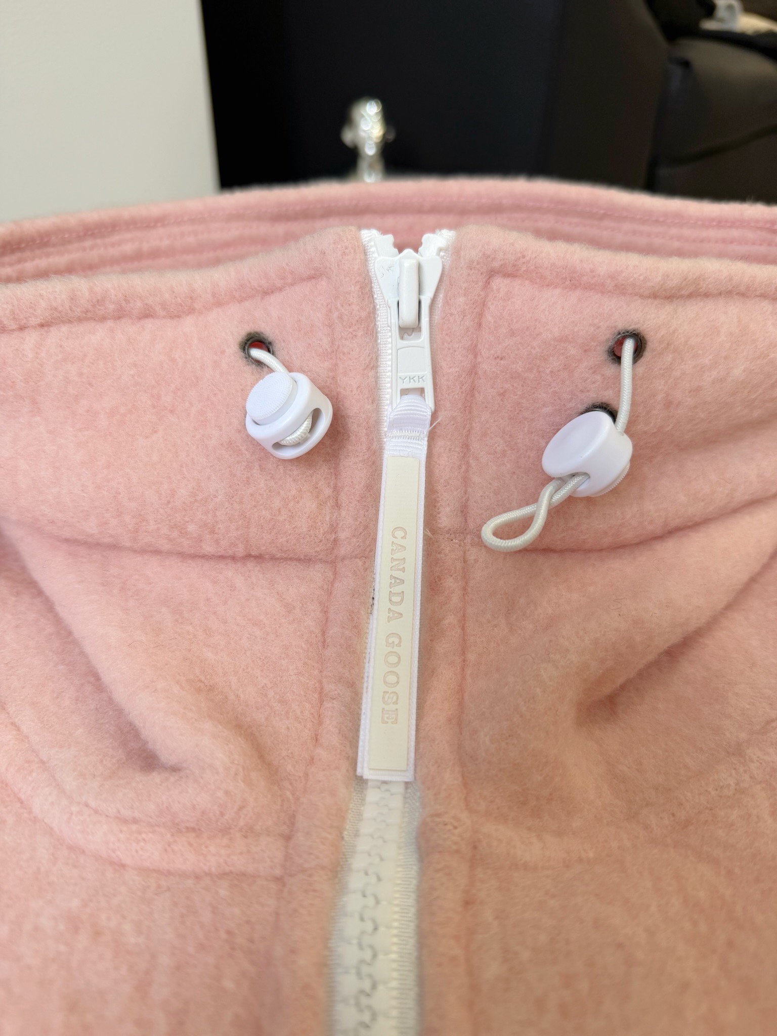 大鹅/Canada Goose抓绒羊毛饰章连帽夹克外套 面料选择: 以羊毛为主体，加入极少量氨纶和聚酯纤维混纺而成的羊毛抓绒面料。羊毛作为核心天然成分，提供无与伦比的温度调节、抑菌防臭和亲肤感。少量氨纶的喂入赋予了面料一定的四向弹性，日常活动时毫无束缚感。作为抓绒结构的基础，聚酯纤维增强了面料的耐久性、抗皱性和快干性，它构成了抓绒的蓬松感，并提供锁住空气等功能。 细节1: 衣袖和下摆采用2乘2罗纹收口，其强大的弹性，可以紧密贴合不同粗细的手腕和腰部，形成一个有效的&lsquo;密封&rsquo;,防止冷风倒灌。在多次拉伸和使用后仍能保持原有形状，不易松垮变形。且罗纹袖口能传递一种设计感，强化视觉美观度。 细节2: 兜帽设计与松紧扣的搭配提升穿戴时的保暖度与防风性能。 辅料:定制弹性抽绳松紧扣定制拉链吊坠定制臂章 尺码：S M L 颜色：黑 灰 咖 米 粉