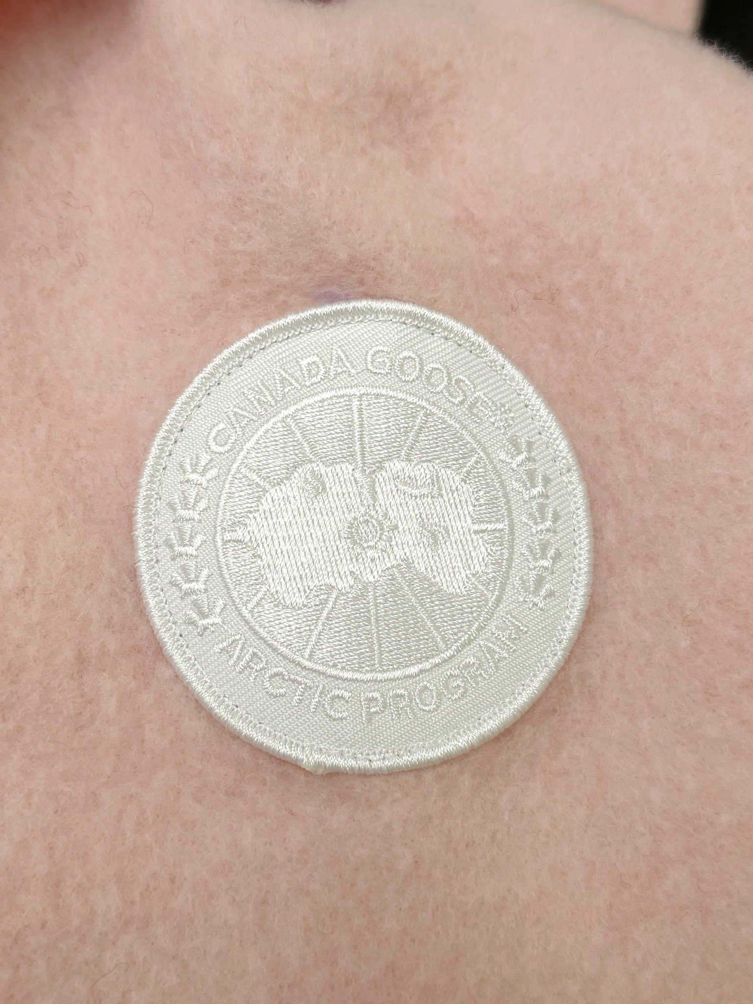 大鹅/Canada Goose抓绒羊毛饰章连帽夹克外套 面料选择: 以羊毛为主体，加入极少量氨纶和聚酯纤维混纺而成的羊毛抓绒面料。羊毛作为核心天然成分，提供无与伦比的温度调节、抑菌防臭和亲肤感。少量氨纶的喂入赋予了面料一定的四向弹性，日常活动时毫无束缚感。作为抓绒结构的基础，聚酯纤维增强了面料的耐久性、抗皱性和快干性，它构成了抓绒的蓬松感，并提供锁住空气等功能。 细节1: 衣袖和下摆采用2乘2罗纹收口，其强大的弹性，可以紧密贴合不同粗细的手腕和腰部，形成一个有效的&lsquo;密封&rsquo;,防止冷风倒灌。在多次拉伸和使用后仍能保持原有形状，不易松垮变形。且罗纹袖口能传递一种设计感，强化视觉美观度。 细节2: 兜帽设计与松紧扣的搭配提升穿戴时的保暖度与防风性能。 辅料:定制弹性抽绳松紧扣定制拉链吊坠定制臂章 尺码：S M L 颜色：黑 灰 咖 米 粉