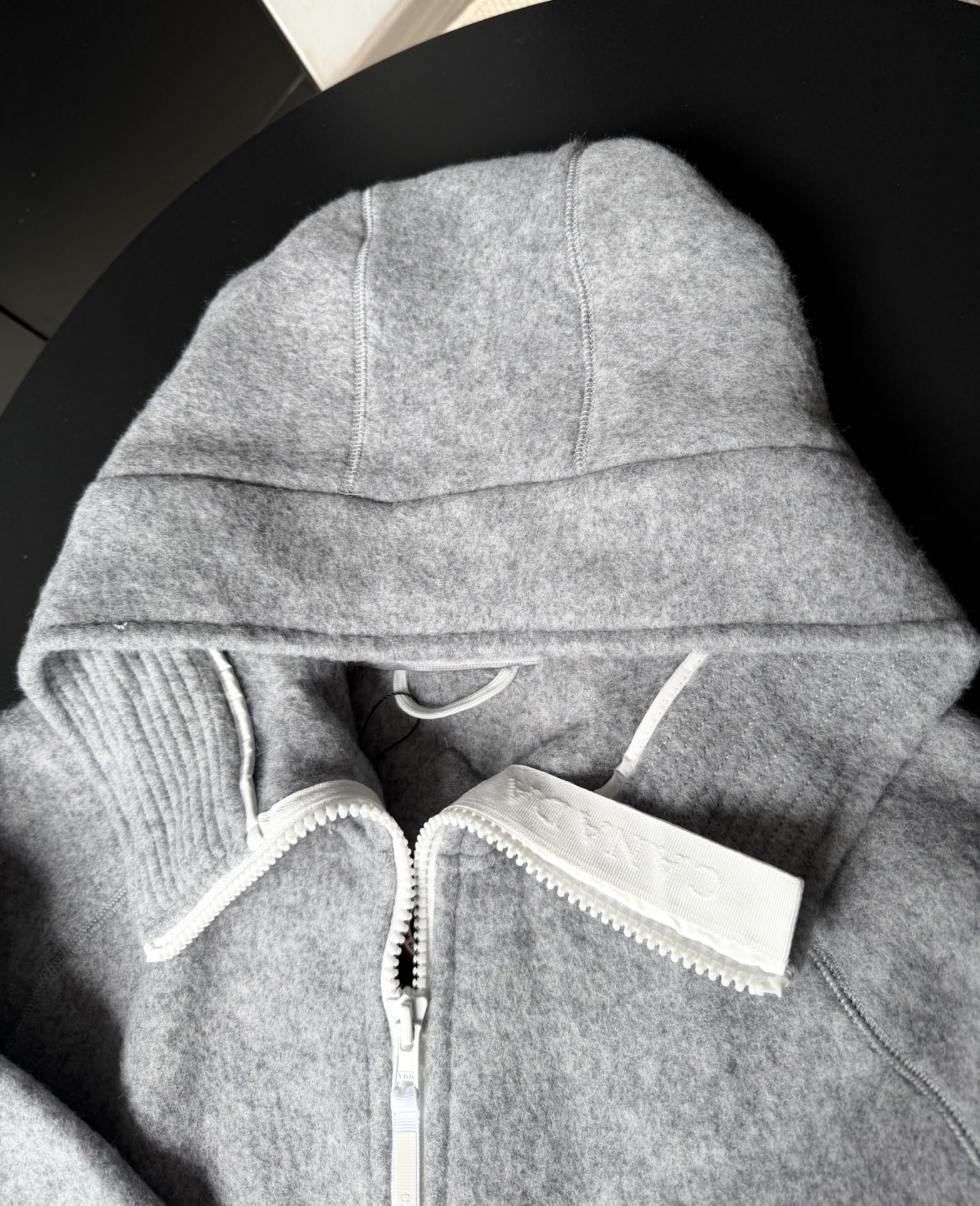 大鹅/Canada Goose抓绒羊毛饰章连帽夹克外套 面料选择: 以羊毛为主体，加入极少量氨纶和聚酯纤维混纺而成的羊毛抓绒面料。羊毛作为核心天然成分，提供无与伦比的温度调节、抑菌防臭和亲肤感。少量氨纶的喂入赋予了面料一定的四向弹性，日常活动时毫无束缚感。作为抓绒结构的基础，聚酯纤维增强了面料的耐久性、抗皱性和快干性，它构成了抓绒的蓬松感，并提供锁住空气等功能。 细节1: 衣袖和下摆采用2乘2罗纹收口，其强大的弹性，可以紧密贴合不同粗细的手腕和腰部，形成一个有效的&lsquo;密封&rsquo;,防止冷风倒灌。在多次拉伸和使用后仍能保持原有形状，不易松垮变形。且罗纹袖口能传递一种设计感，强化视觉美观度。 细节2: 兜帽设计与松紧扣的搭配提升穿戴时的保暖度与防风性能。 辅料:定制弹性抽绳松紧扣定制拉链吊坠定制臂章 尺码：S M L 颜色：黑 灰 咖 米 粉