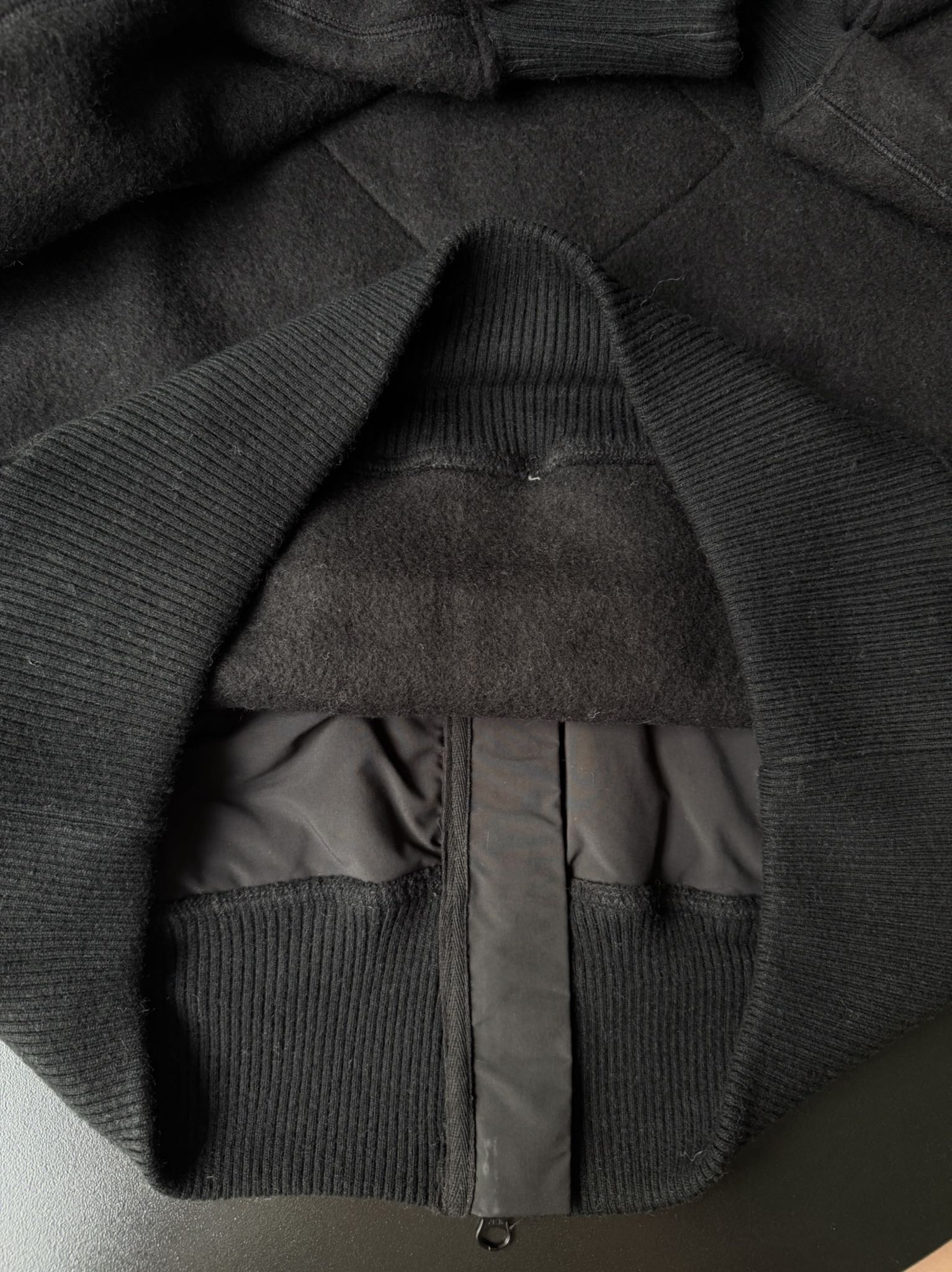 大鹅/Canada Goose抓绒羊毛饰章连帽夹克外套 面料选择: 以羊毛为主体，加入极少量氨纶和聚酯纤维混纺而成的羊毛抓绒面料。羊毛作为核心天然成分，提供无与伦比的温度调节、抑菌防臭和亲肤感。少量氨纶的喂入赋予了面料一定的四向弹性，日常活动时毫无束缚感。作为抓绒结构的基础，聚酯纤维增强了面料的耐久性、抗皱性和快干性，它构成了抓绒的蓬松感，并提供锁住空气等功能。 细节1: 衣袖和下摆采用2乘2罗纹收口，其强大的弹性，可以紧密贴合不同粗细的手腕和腰部，形成一个有效的&lsquo;密封&rsquo;,防止冷风倒灌。在多次拉伸和使用后仍能保持原有形状，不易松垮变形。且罗纹袖口能传递一种设计感，强化视觉美观度。 细节2: 兜帽设计与松紧扣的搭配提升穿戴时的保暖度与防风性能。 辅料:定制弹性抽绳松紧扣定制拉链吊坠定制臂章 尺码：S M L 颜色：黑 灰 咖 米 粉