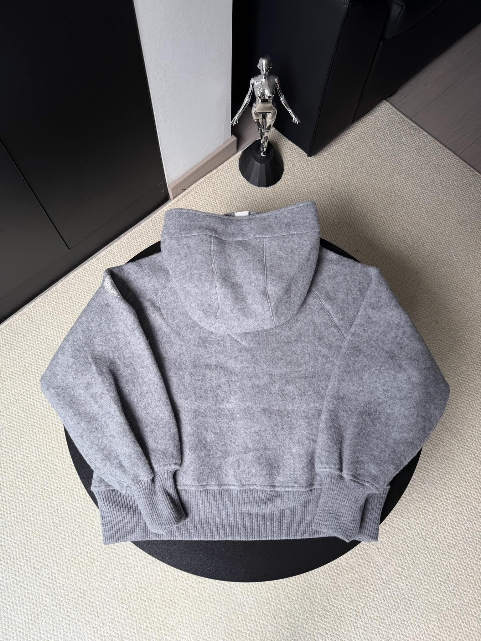 大鹅/Canada Goose抓绒羊毛饰章连帽夹克外套 面料选择: 以羊毛为主体，加入极少量氨纶和聚酯纤维混纺而成的羊毛抓绒面料。羊毛作为核心天然成分，提供无与伦比的温度调节、抑菌防臭和亲肤感。少量氨纶的喂入赋予了面料一定的四向弹性，日常活动时毫无束缚感。作为抓绒结构的基础，聚酯纤维增强了面料的耐久性、抗皱性和快干性，它构成了抓绒的蓬松感，并提供锁住空气等功能。 细节1: 衣袖和下摆采用2乘2罗纹收口，其强大的弹性，可以紧密贴合不同粗细的手腕和腰部，形成一个有效的&lsquo;密封&rsquo;,防止冷风倒灌。在多次拉伸和使用后仍能保持原有形状，不易松垮变形。且罗纹袖口能传递一种设计感，强化视觉美观度。 细节2: 兜帽设计与松紧扣的搭配提升穿戴时的保暖度与防风性能。 辅料:定制弹性抽绳松紧扣定制拉链吊坠定制臂章 尺码：S M L 颜色：黑 灰 咖 米 粉