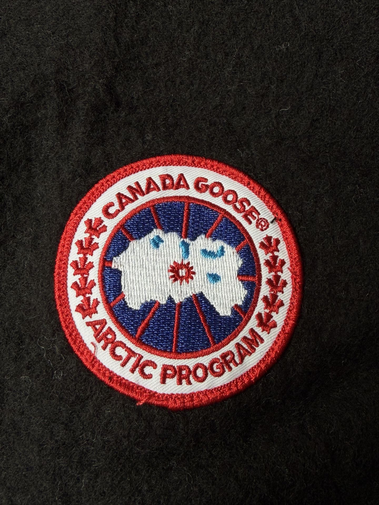 大鹅/Canada Goose抓绒羊毛饰章连帽夹克外套 面料选择: 以羊毛为主体，加入极少量氨纶和聚酯纤维混纺而成的羊毛抓绒面料。羊毛作为核心天然成分，提供无与伦比的温度调节、抑菌防臭和亲肤感。少量氨纶的喂入赋予了面料一定的四向弹性，日常活动时毫无束缚感。作为抓绒结构的基础，聚酯纤维增强了面料的耐久性、抗皱性和快干性，它构成了抓绒的蓬松感，并提供锁住空气等功能。 细节1: 衣袖和下摆采用2乘2罗纹收口，其强大的弹性，可以紧密贴合不同粗细的手腕和腰部，形成一个有效的&lsquo;密封&rsquo;,防止冷风倒灌。在多次拉伸和使用后仍能保持原有形状，不易松垮变形。且罗纹袖口能传递一种设计感，强化视觉美观度。 细节2: 兜帽设计与松紧扣的搭配提升穿戴时的保暖度与防风性能。 辅料:定制弹性抽绳松紧扣定制拉链吊坠定制臂章 尺码：S M L 颜色：黑 灰 咖 米 粉