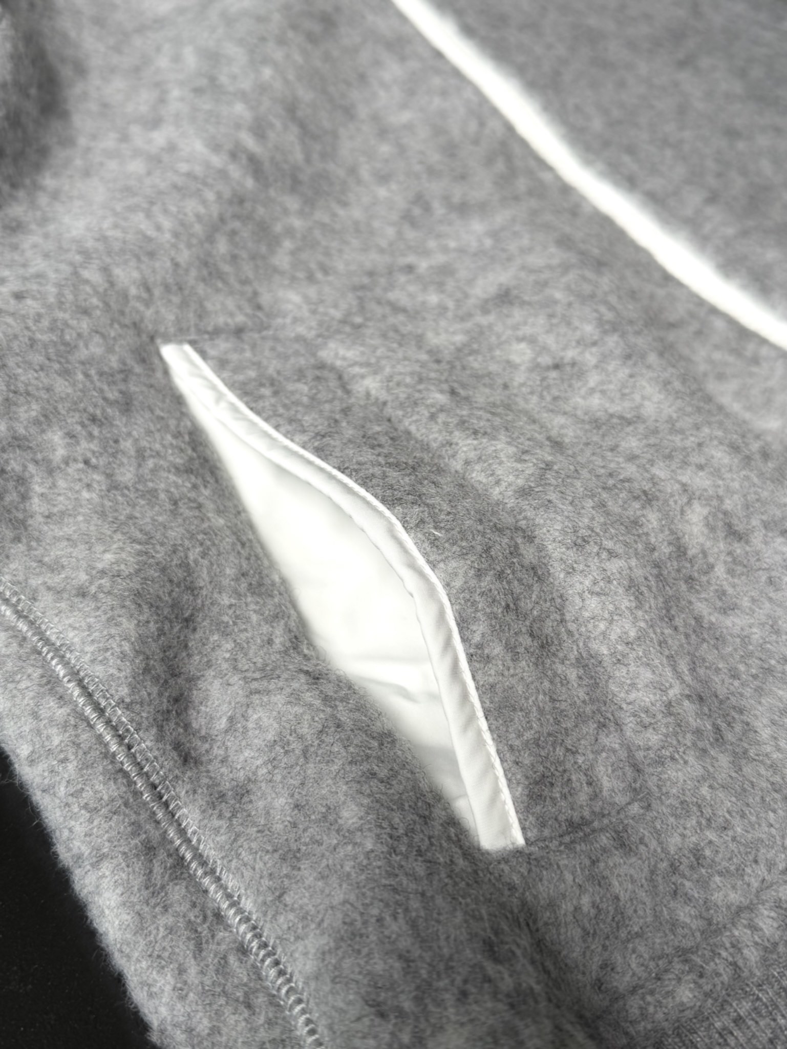 大鹅/Canada Goose抓绒羊毛饰章连帽夹克外套 面料选择: 以羊毛为主体，加入极少量氨纶和聚酯纤维混纺而成的羊毛抓绒面料。羊毛作为核心天然成分，提供无与伦比的温度调节、抑菌防臭和亲肤感。少量氨纶的喂入赋予了面料一定的四向弹性，日常活动时毫无束缚感。作为抓绒结构的基础，聚酯纤维增强了面料的耐久性、抗皱性和快干性，它构成了抓绒的蓬松感，并提供锁住空气等功能。 细节1: 衣袖和下摆采用2乘2罗纹收口，其强大的弹性，可以紧密贴合不同粗细的手腕和腰部，形成一个有效的&lsquo;密封&rsquo;,防止冷风倒灌。在多次拉伸和使用后仍能保持原有形状，不易松垮变形。且罗纹袖口能传递一种设计感，强化视觉美观度。 细节2: 兜帽设计与松紧扣的搭配提升穿戴时的保暖度与防风性能。 辅料:定制弹性抽绳松紧扣定制拉链吊坠定制臂章 尺码：S M L 颜色：黑 灰 咖 米 粉