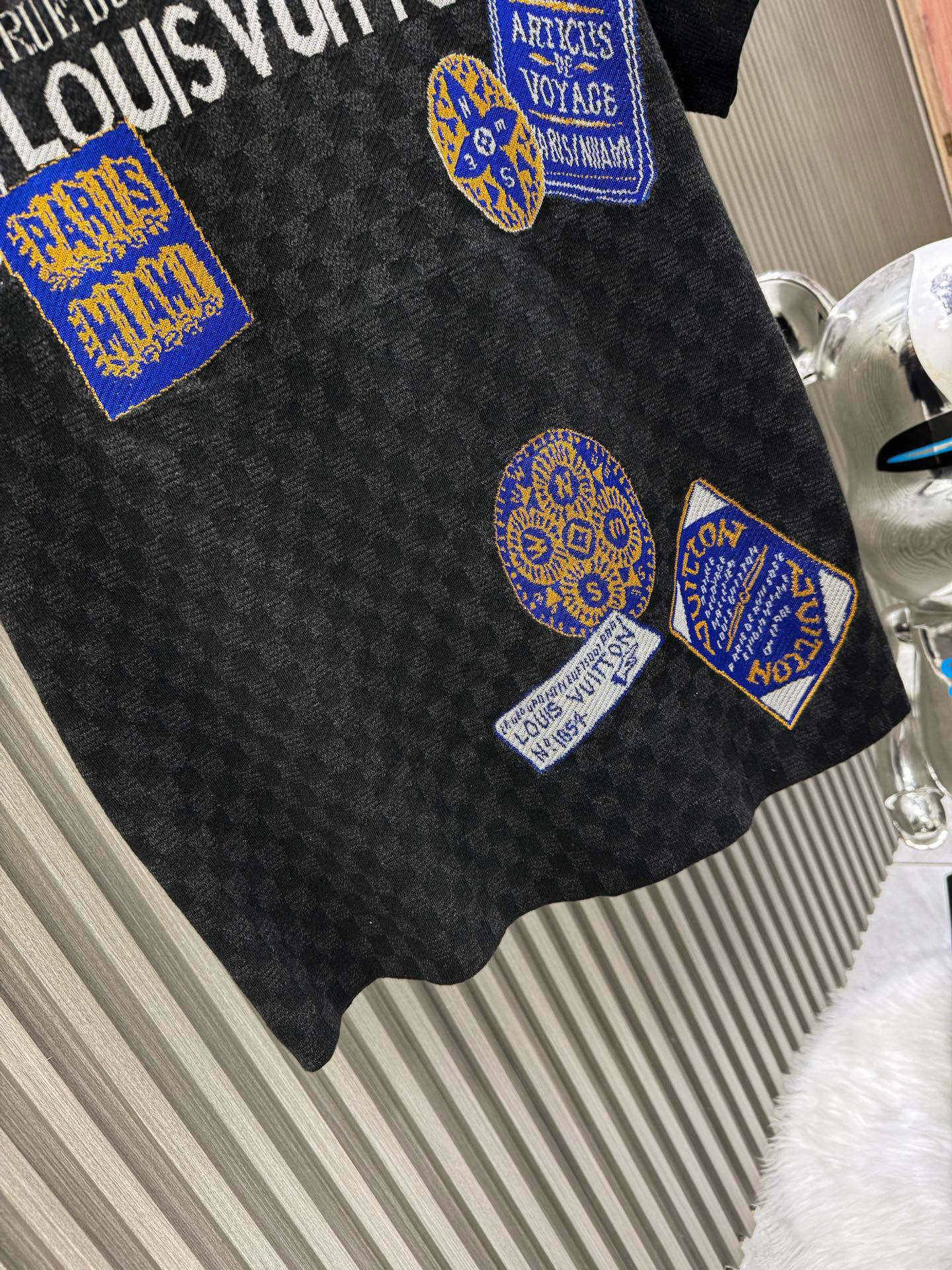 💰200🀄️ Louis Vuitton路易威登 LOUIS VUITTON 棋盘格标签针织短袖 采用定制棉质加光丝面料匠心制作 Damier提花嵌花织纹 德国进口挂毛机织片而成 织线原衣对色 环保固色定染 提花面料要求纱支精细衣身运用进口16针织令士提方格织法完美跟提花工艺每件耗时要150分钟 图案采取双面挂毛工艺 精细做工 肌理纹路清晰 极细织线由环保纤维打造 缝合采用的是16针盘 每个收口还要手工挑 缝线都要松紧一致要平顺 出品大身前后左右整齐对位理衣身面料具有软糯垂坠触感 面料舒适柔软 亲肤透气 富有弹性 全衣以棋盘格底纹 胸前品牌字母刺绣 配蓝色徽章设计感十足 和袖子均有品牌 细节做工精致 整体走线平直细腻 面料舒适柔软 颜色一致无色差 能与同款搭配营造时尚造型 三标齐全 男女同款