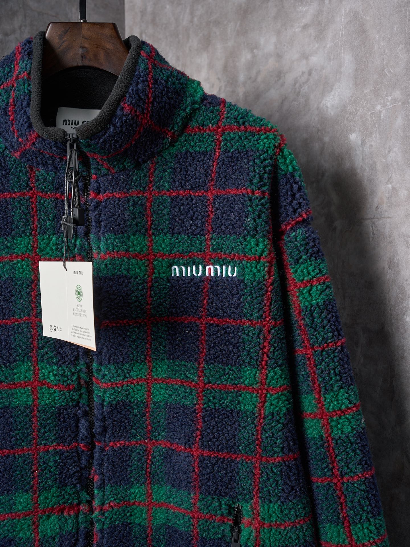 💰260【实物挂拍】MiuMiu/缪缪 羊羔绒格子刺绣拉链外套 【颜色】绿色 灰色 【现货】S M L XL 经典夹克在这款中被重新诠释，加入羊毛以增加厚度和柔软度。经典格纹图案汲取男装风格灵感，重新诠释运动女性气质的风格密码。 Oversize版型. 无衬里长袖立领.正面拉链开合 侧袋.双头钩针底边.刺绣徽标 采用80%羊毛，20%棉。该款面料原版定织定染，100%还原。内衬口袋布采用100%尼龙料， 后领位置搭配100%羊毛泰迪绒。 拉链采用尼龙与胶牙材料结合，拉牙采用欧款胶牙。下摆搭配原版刻字弹力扣。 刺绣采用3D立体刺绣工艺，刺绣logo饱满立体。呈现出高端视觉效果。