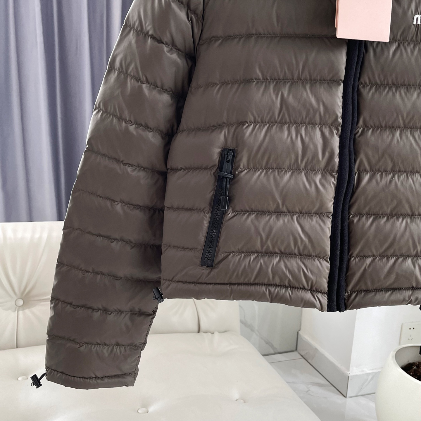 MiuMiu缪缪【冬日奢暖，型格兼备】 新款排骨连帽羽绒服外套女款 以简约轮廓勾勒高级气场。连帽设计与黑色抽绳细节，兼顾实用与时尚感。森林绿色与黑色羊绒包边撞色高级，增添层次感。左胸经典MIUMIU标志低调诠释品牌基因，优质羽绒填充锁住暖意。 无论是都市漫步还是休闲出行，皆能从容驾驭冬日氛围，赋予你温暖与风格并存的穿搭体验。 原版购入打版打色，开模定制五金辅料，三标齐全，1:1完美复刻。市面最高版！ 尺码：S/M/L