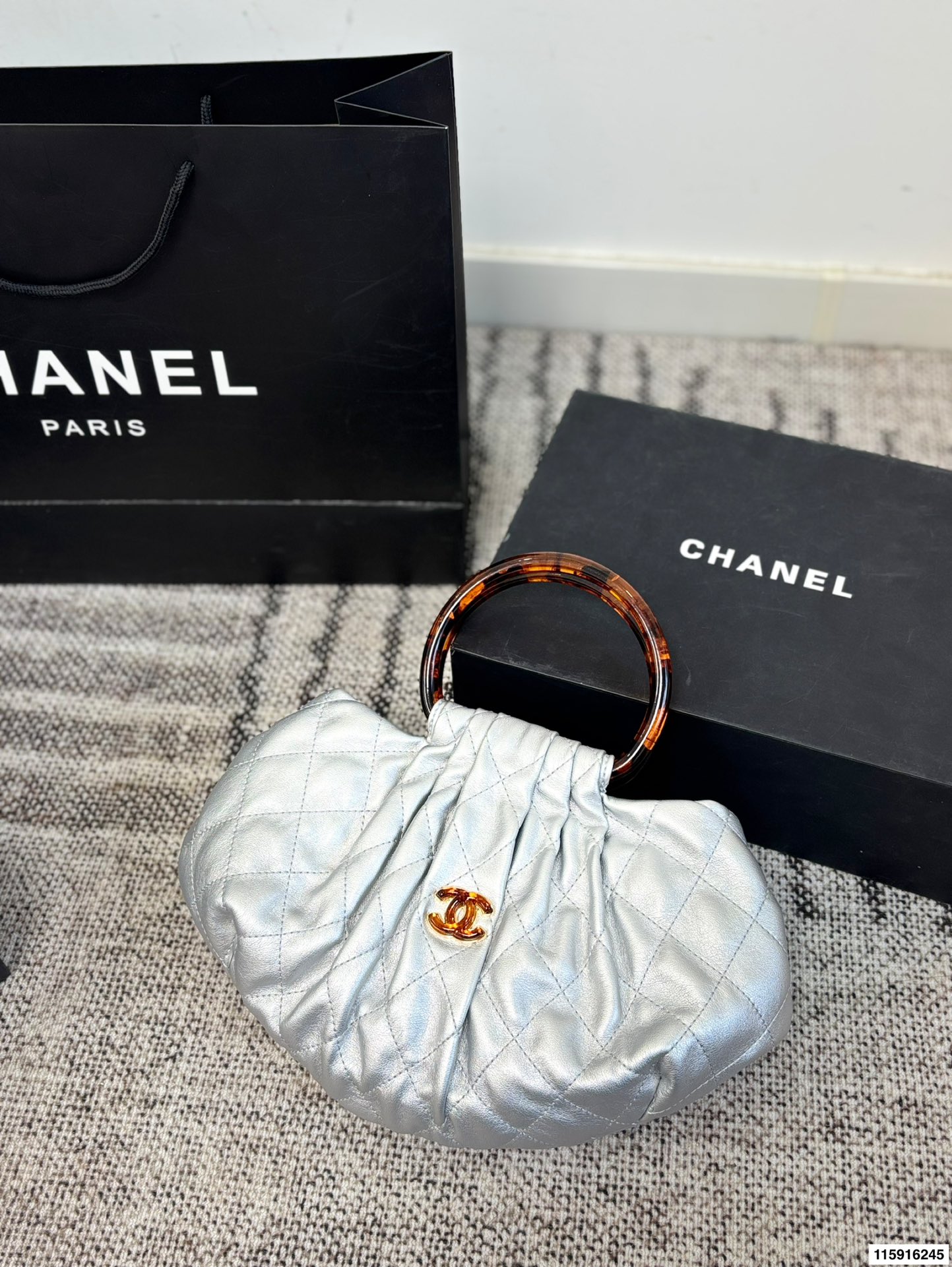 p145 配折叠盒 Chanel 26C玳瑁手柄福袋包 Chanel 26C早春系列福袋包，黑色麂皮+玳瑁色手柄，复古优雅感满满十。经典菱格纹缝线+双CLogo，细节超精致，手机小物轻松收纳，麂皮柔软，秋冬搭配超有氛围感 。玳瑁手柄光泽感强，手提或复古风都很出彩，实用又时髦，是热门单品！ 尺寸 30.20