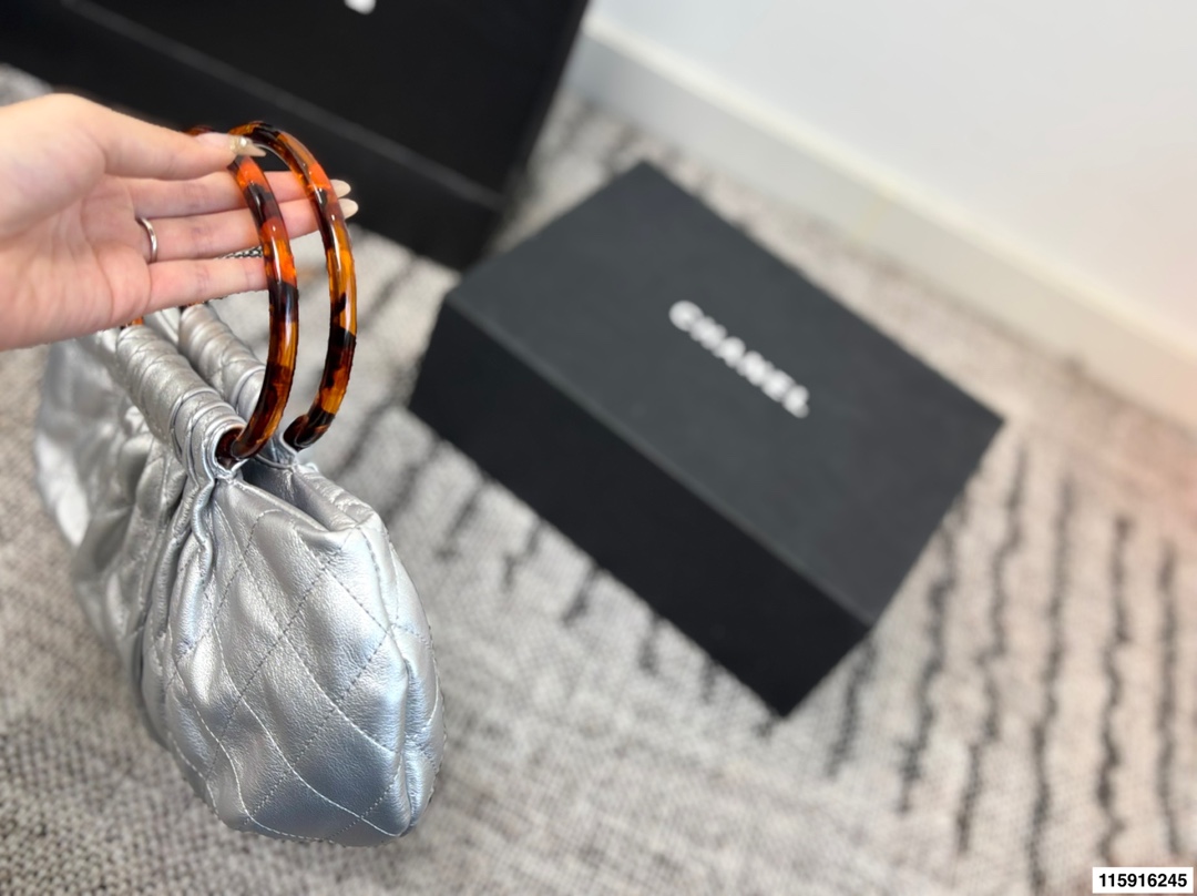 p145 配折叠盒 Chanel 26C玳瑁手柄福袋包 Chanel 26C早春系列福袋包，黑色麂皮+玳瑁色手柄，复古优雅感满满十。经典菱格纹缝线+双CLogo，细节超精致，手机小物轻松收纳，麂皮柔软，秋冬搭配超有氛围感 。玳瑁手柄光泽感强，手提或复古风都很出彩，实用又时髦，是热门单品！ 尺寸 30.20