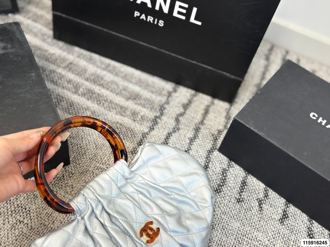 p145 配折叠盒 Chanel 26C玳瑁手柄福袋包 Chanel 26C早春系列福袋包，黑色麂皮+玳瑁色手柄，复古优雅感满满十。经典菱格纹缝线+双CLogo，细节超精致，手机小物轻松收纳，麂皮柔软，秋冬搭配超有氛围感 。玳瑁手柄光泽感强，手提或复古风都很出彩，实用又时髦，是热门单品！ 尺寸 30.20