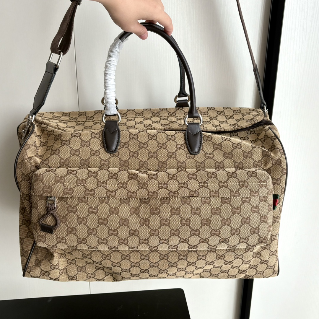 实拍#💰280 款号：802095 尺寸：45/28/24cm 秋冬男士系列经典旅行单品生动展现运动风格。该系列旅行单品采用OriginalGG帆布制作，经典配饰搭配甄选配色，织带和压花标识等精致细节传递时尚气息。这款旅行包以米色和乌木色帆布打造，搭配一个外部口袋、顶部提手和D形环。