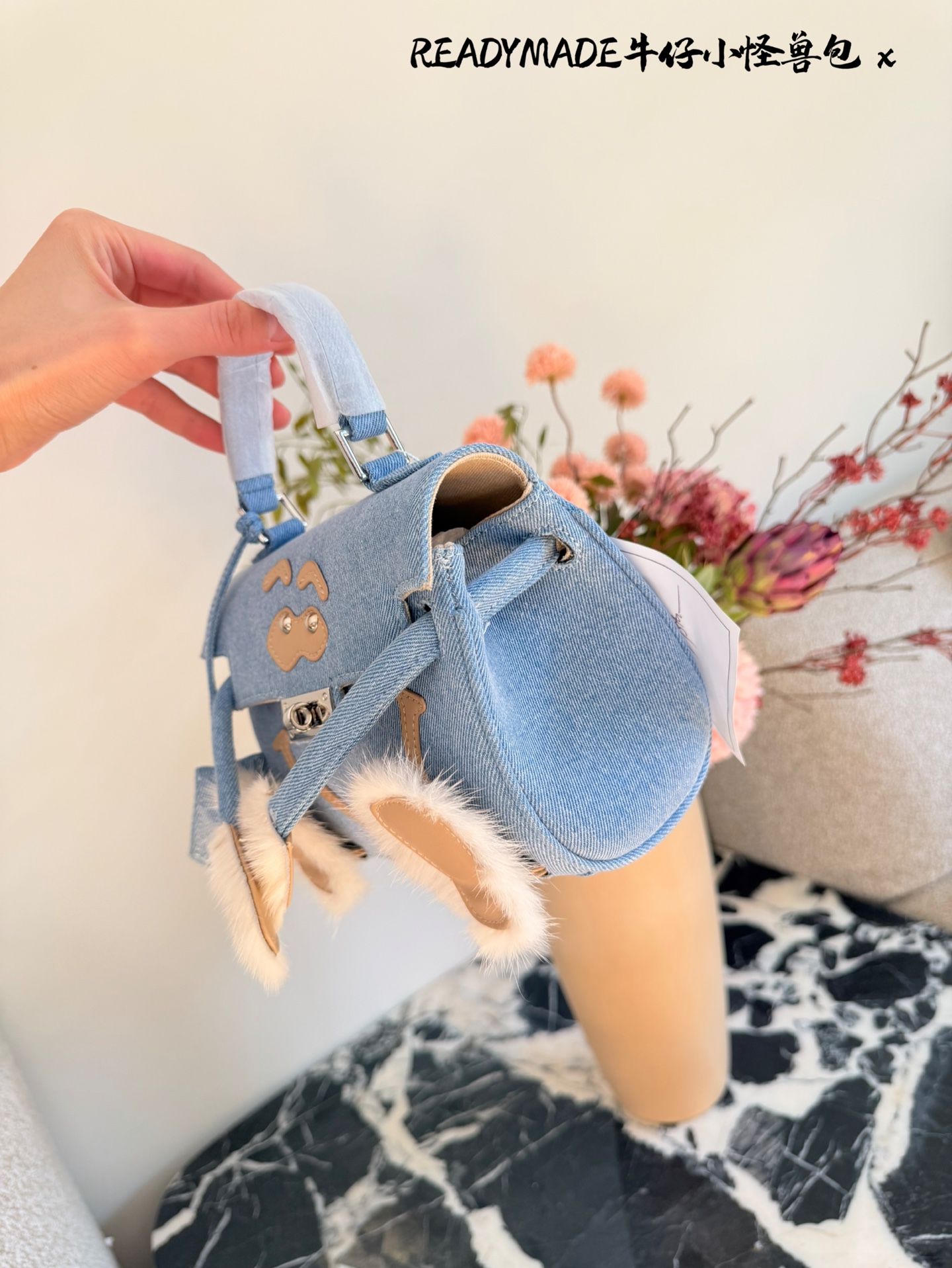 p215 READYMADE牛仔小怪兽包 国日本小众品牌READYMADE的牛仔小怪兽包，灵感来 自爱马仕Kelly Doll,浅蓝牛仔布+貂毛手脚，手感超柔软，趣味满分汁。迷你尺寸约18cm，能装手机、气垫等日常小物，手拎斜挎都OK，街头风、甜酷风都能轻松驾驭!部分配色已停产，收藏价值高，超适合喜欢个性和可爱风的姐妹们。