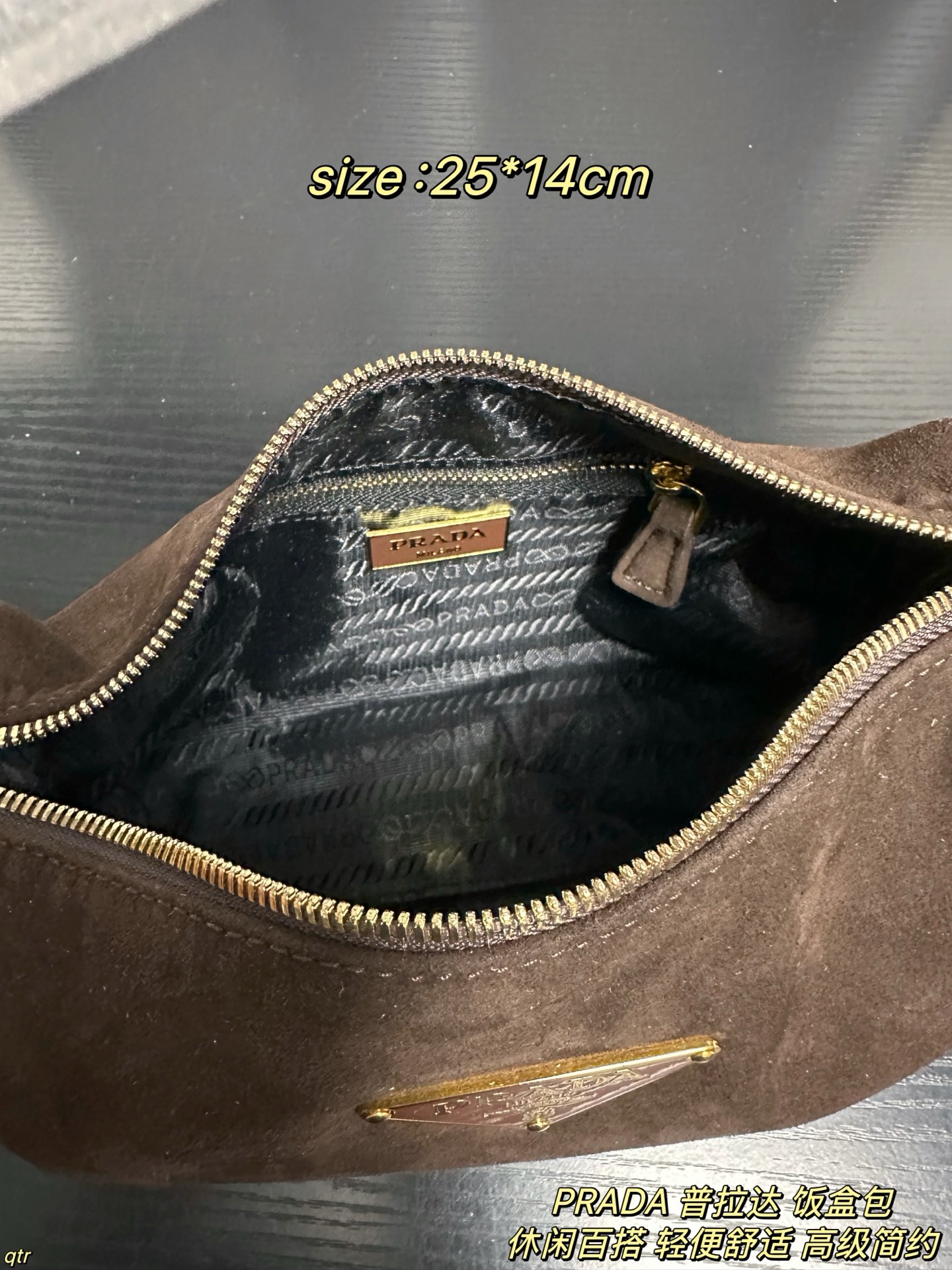P105配盒 PRADA 普拉达 饭盒包 这款包采用进口麂皮，具有柔软的轮廓和多个口袋，轻质实用的Re-Nylon强调了设计的多功能风格，而皮革细节和标志性点缀则反映了Prada的手工传统，配有2条可拆卸、可调节的编织标志带肩带，容量空间大，上身效果非常时尚。又是一款永久不过时爆款。值得拥有 尺寸：25*14cm