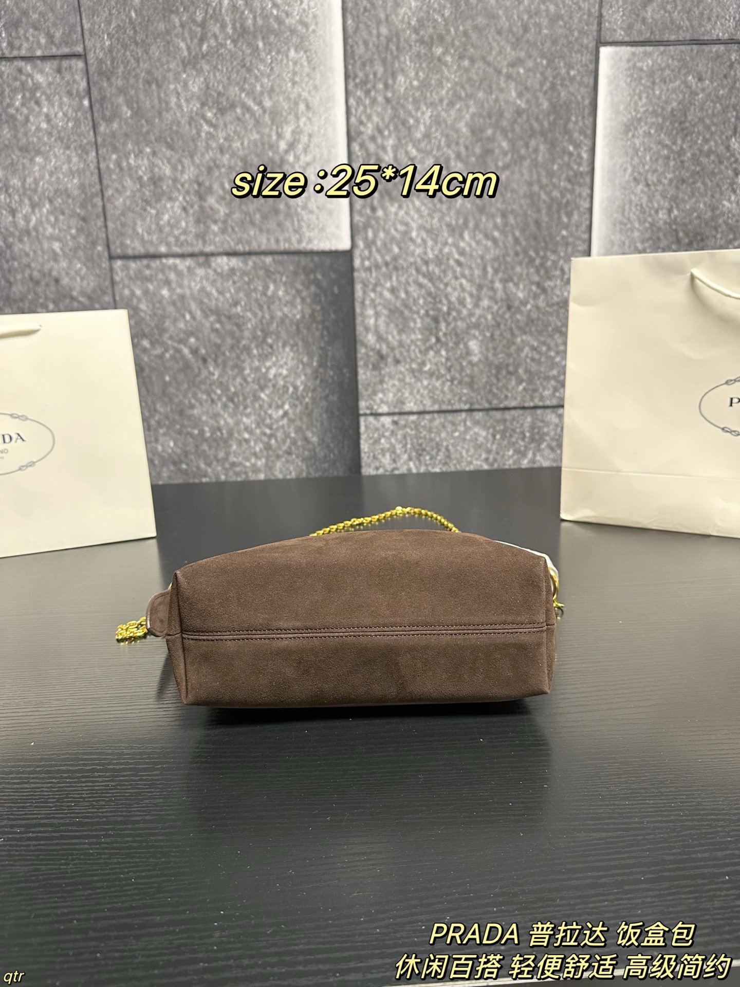 P105配盒 PRADA 普拉达 饭盒包 这款包采用进口麂皮，具有柔软的轮廓和多个口袋，轻质实用的Re-Nylon强调了设计的多功能风格，而皮革细节和标志性点缀则反映了Prada的手工传统，配有2条可拆卸、可调节的编织标志带肩带，容量空间大，上身效果非常时尚。又是一款永久不过时爆款。值得拥有 尺寸：25*14cm