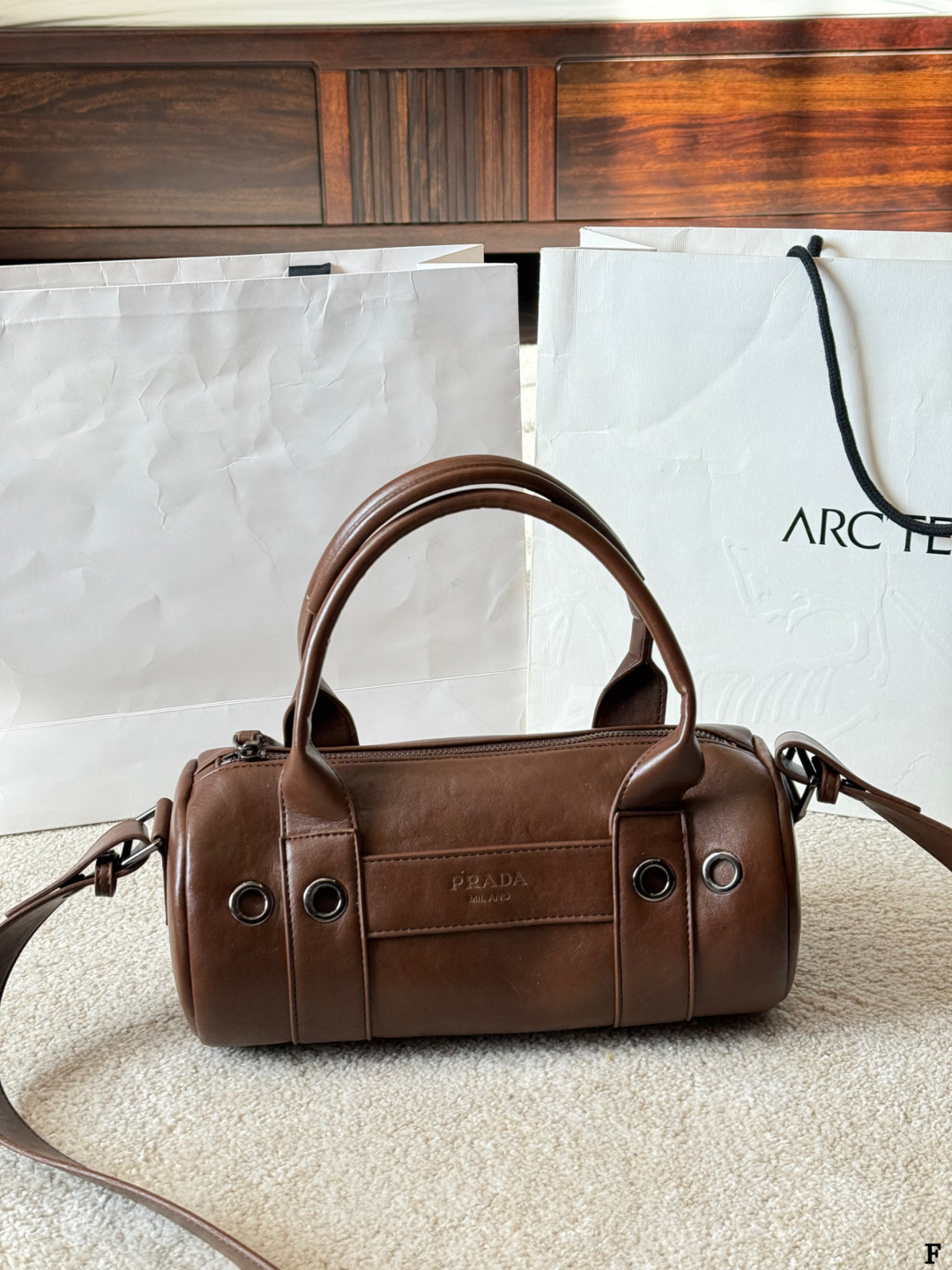 p170 Prada 26SS圆筒包 些Prada 26SS圆筒包是春夏系列新品，棕色皮革质感细腻耐用，简约复古风格超有范！圆筒造型+双提手+可拆卸肩带，手提斜挎都OK，通勤休闲都能搭。正面Logo低调有辨识度，金属环扣点缀细节满分。日本快闪首发，稀缺属性，时尚实用，Prada粉丝必入！ 尺寸 30 15cm