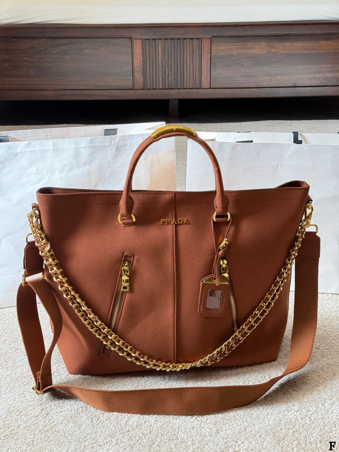 p190 Prada链条托特包 Prada这款棕色链条托特包，采用优质牛皮，手感细腻耐用。金属链条+皮革肩带，手提斜挎都OK，超百搭！正面Logo低调有辦识度，内部空间超大，通勤or短途旅行都能装下日常用品。拉链口袋设计，收纳更方便，实用又时髦，是都市女生的热门选择！ 尺寸 35 33cm
