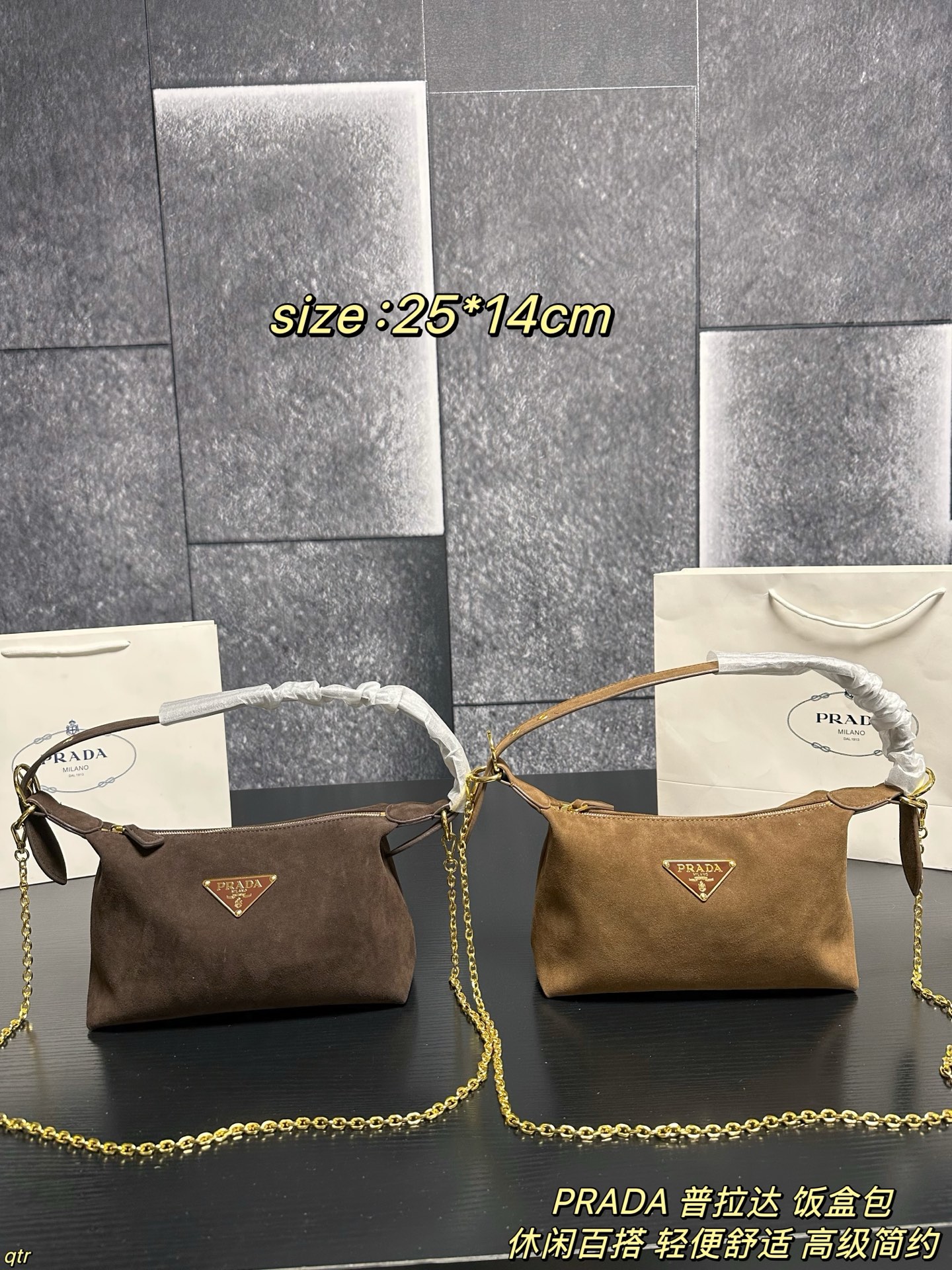 P105配盒 PRADA 普拉达 饭盒包 这款包采用进口麂皮，具有柔软的轮廓和多个口袋，轻质实用的Re-Nylon强调了设计的多功能风格，而皮革细节和标志性点缀则反映了Prada的手工传统，配有2条可拆卸、可调节的编织标志带肩带，容量空间大，上身效果非常时尚。又是一款永久不过时爆款。值得拥有 尺寸：25*14cm