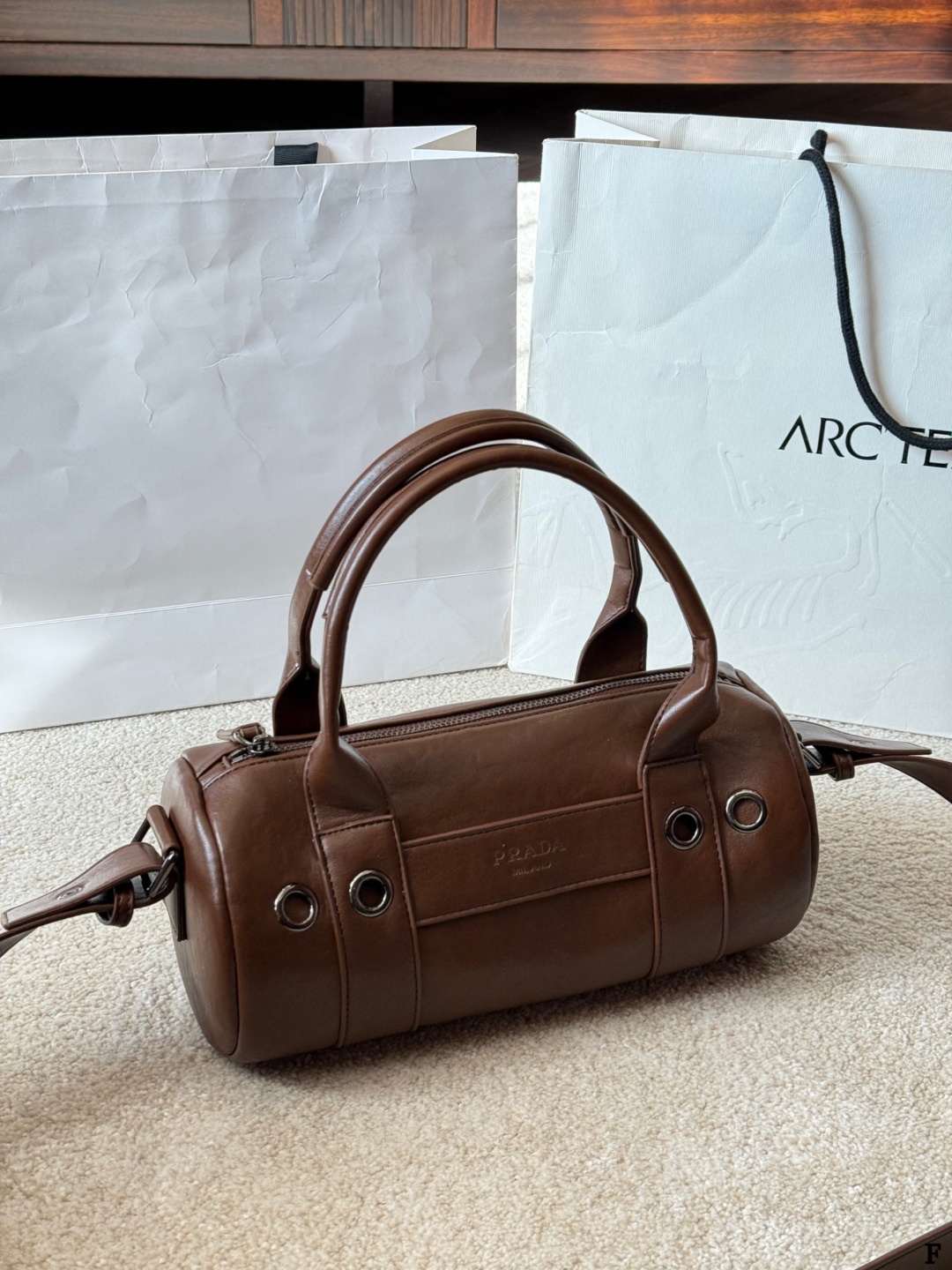 p170 Prada 26SS圆筒包 些Prada 26SS圆筒包是春夏系列新品，棕色皮革质感细腻耐用，简约复古风格超有范！圆筒造型+双提手+可拆卸肩带，手提斜挎都OK，通勤休闲都能搭。正面Logo低调有辨识度，金属环扣点缀细节满分。日本快闪首发，稀缺属性，时尚实用，Prada粉丝必入！ 尺寸 30 15cm