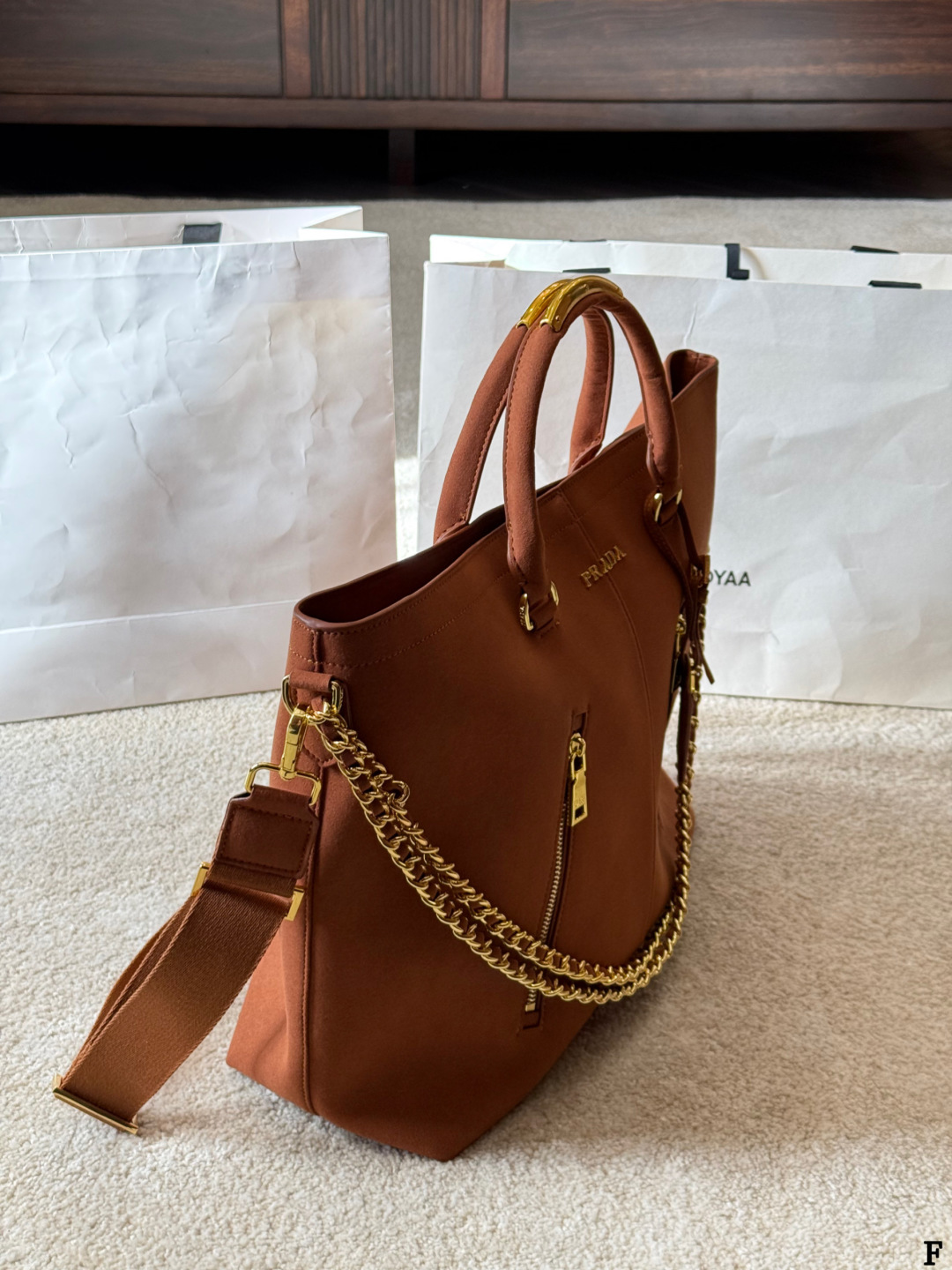 p190 Prada链条托特包 Prada这款棕色链条托特包，采用优质牛皮，手感细腻耐用。金属链条+皮革肩带，手提斜挎都OK，超百搭！正面Logo低调有辦识度，内部空间超大，通勤or短途旅行都能装下日常用品。拉链口袋设计，收纳更方便，实用又时髦，是都市女生的热门选择！ 尺寸 35 33cm