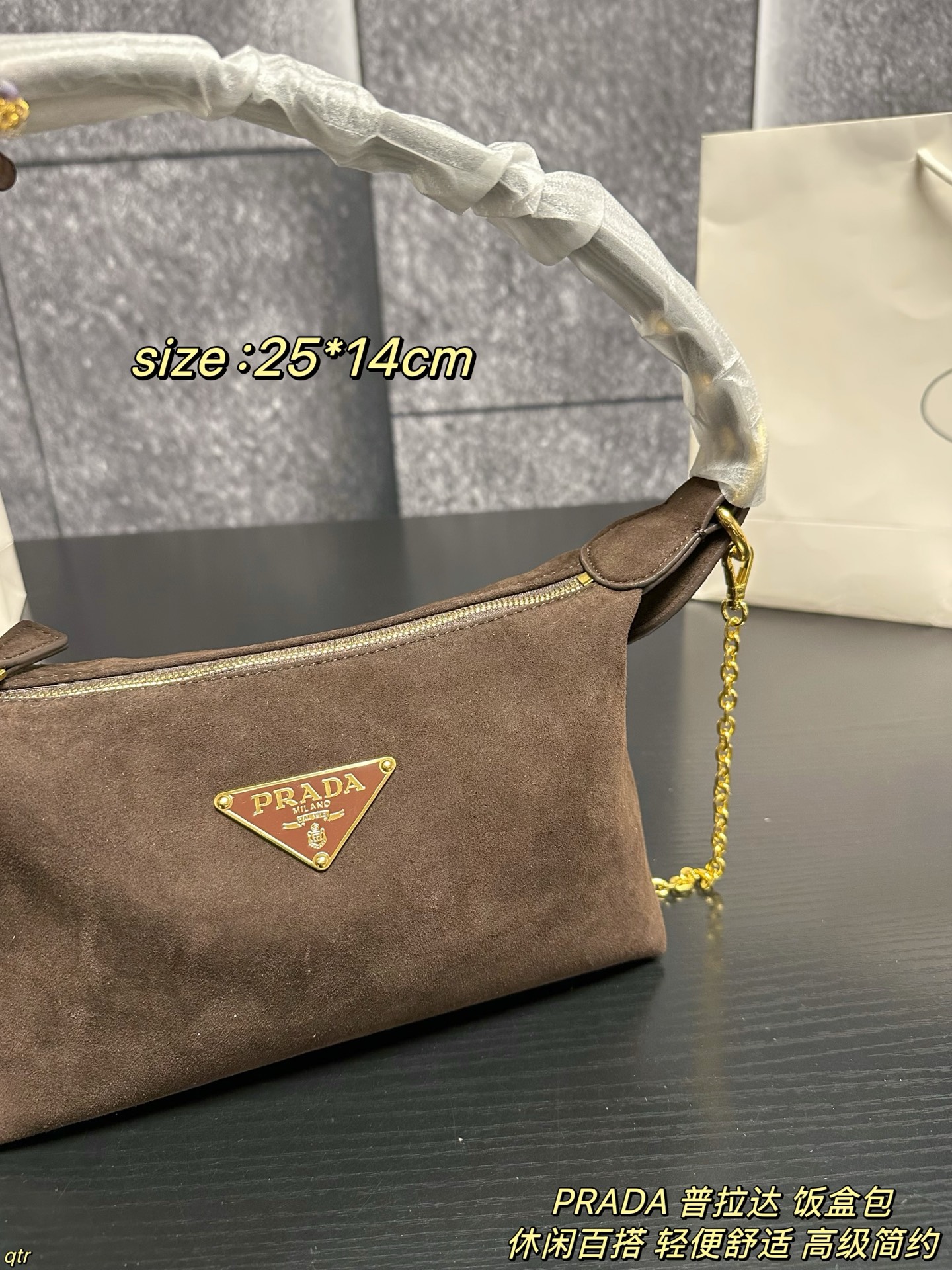 P105配盒 PRADA 普拉达 饭盒包 这款包采用进口麂皮，具有柔软的轮廓和多个口袋，轻质实用的Re-Nylon强调了设计的多功能风格，而皮革细节和标志性点缀则反映了Prada的手工传统，配有2条可拆卸、可调节的编织标志带肩带，容量空间大，上身效果非常时尚。又是一款永久不过时爆款。值得拥有 尺寸：25*14cm