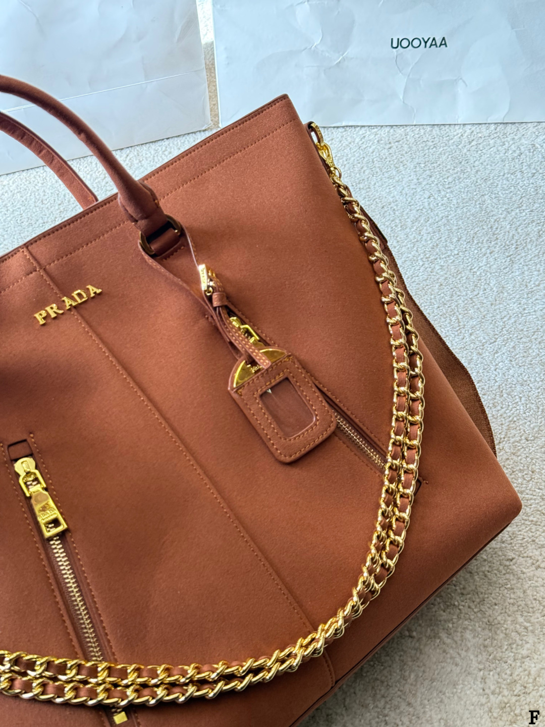 p190 Prada链条托特包 Prada这款棕色链条托特包，采用优质牛皮，手感细腻耐用。金属链条+皮革肩带，手提斜挎都OK，超百搭！正面Logo低调有辦识度，内部空间超大，通勤or短途旅行都能装下日常用品。拉链口袋设计，收纳更方便，实用又时髦，是都市女生的热门选择！ 尺寸 35 33cm