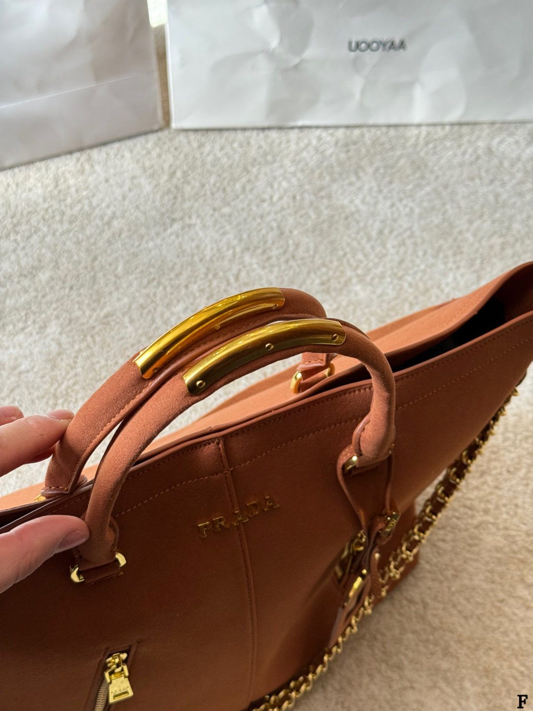 p190 Prada链条托特包 Prada这款棕色链条托特包，采用优质牛皮，手感细腻耐用。金属链条+皮革肩带，手提斜挎都OK，超百搭！正面Logo低调有辦识度，内部空间超大，通勤or短途旅行都能装下日常用品。拉链口袋设计，收纳更方便，实用又时髦，是都市女生的热门选择！ 尺寸 35 33cm
