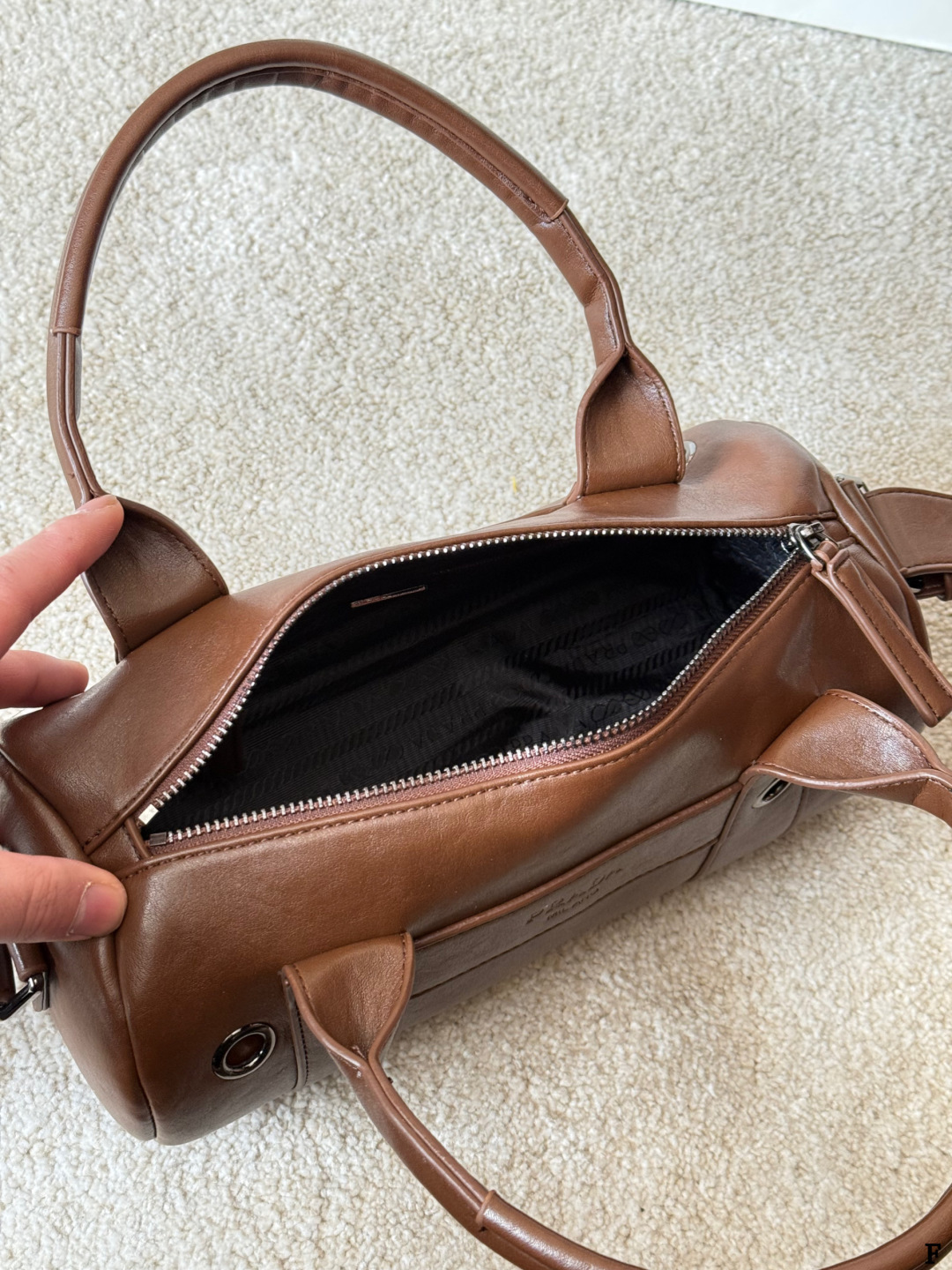 p170 Prada 26SS圆筒包 些Prada 26SS圆筒包是春夏系列新品，棕色皮革质感细腻耐用，简约复古风格超有范！圆筒造型+双提手+可拆卸肩带，手提斜挎都OK，通勤休闲都能搭。正面Logo低调有辨识度，金属环扣点缀细节满分。日本快闪首发，稀缺属性，时尚实用，Prada粉丝必入！ 尺寸 30 15cm