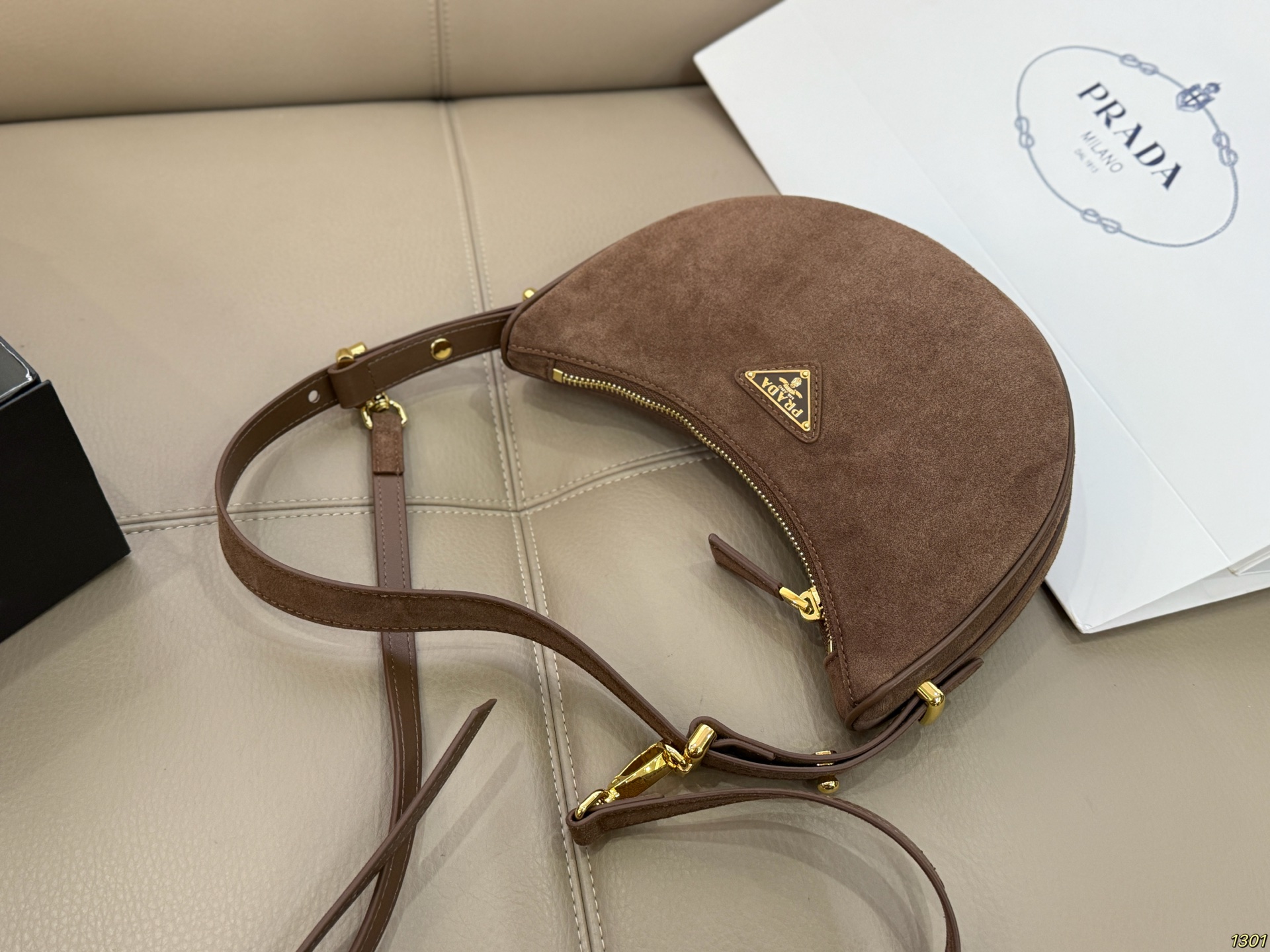 &yen;180 Prada 普拉达 Araue麂皮月牙腋下包 弧形乡设计灵感源自新月，皮革＋珐琅三角徽标，低调优雅又超有辨识度。双肩带设计，手提肩背都OK，容量适中，通勤休闲都能用。新月造型寓意新生与圆满，实用又时髦，是本季超火单品，明星博主都在背！搭配简约或复古穿搭，气质直接拉满尺寸23*13