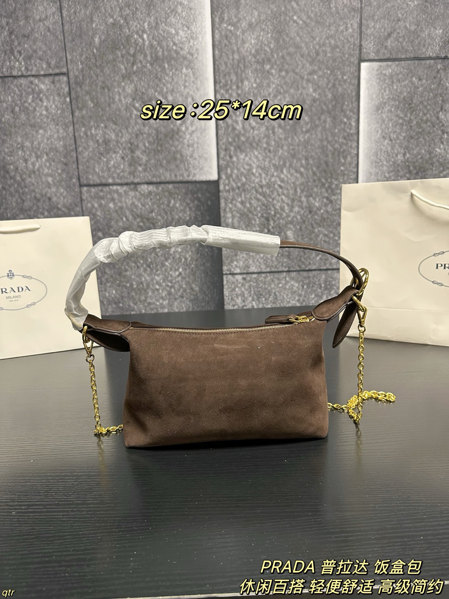 P105配盒 PRADA 普拉达 饭盒包 这款包采用进口麂皮，具有柔软的轮廓和多个口袋，轻质实用的Re-Nylon强调了设计的多功能风格，而皮革细节和标志性点缀则反映了Prada的手工传统，配有2条可拆卸、可调节的编织标志带肩带，容量空间大，上身效果非常时尚。又是一款永久不过时爆款。值得拥有 尺寸：25*14cm