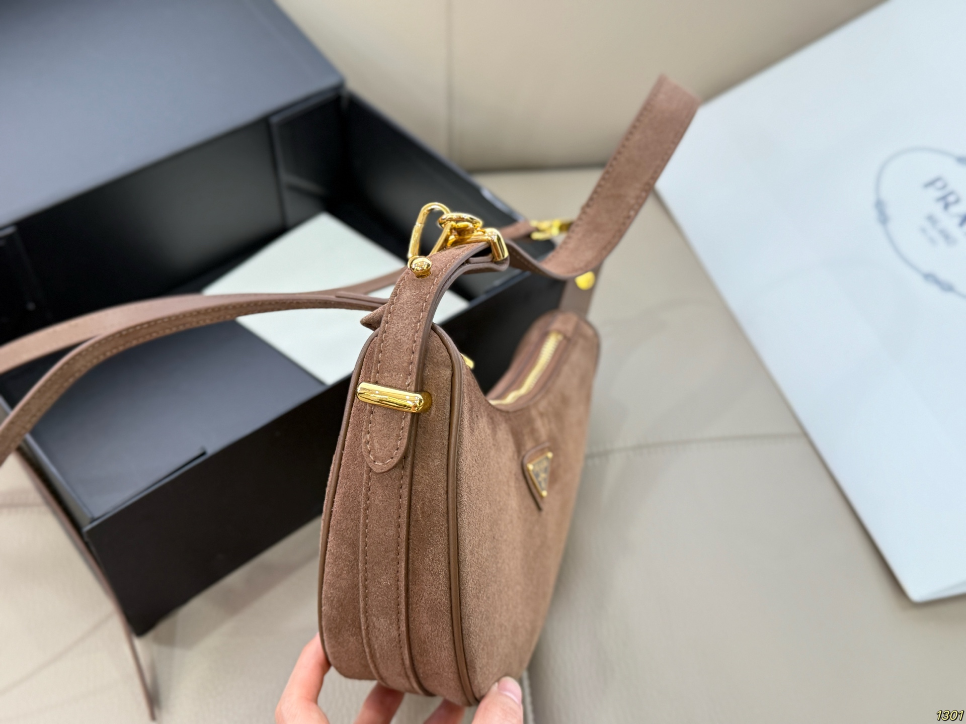 &yen;180 Prada 普拉达 Araue麂皮月牙腋下包 弧形乡设计灵感源自新月，皮革＋珐琅三角徽标，低调优雅又超有辨识度。双肩带设计，手提肩背都OK，容量适中，通勤休闲都能用。新月造型寓意新生与圆满，实用又时髦，是本季超火单品，明星博主都在背！搭配简约或复古穿搭，气质直接拉满尺寸23*13