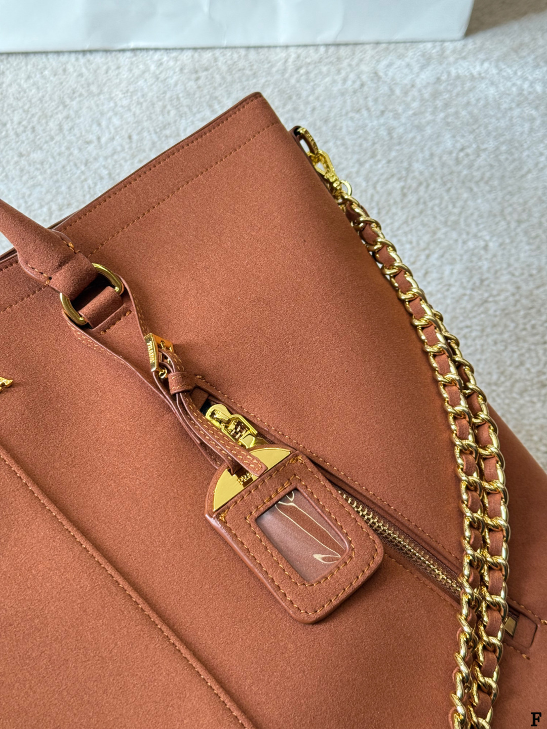 p190 Prada链条托特包 Prada这款棕色链条托特包，采用优质牛皮，手感细腻耐用。金属链条+皮革肩带，手提斜挎都OK，超百搭！正面Logo低调有辦识度，内部空间超大，通勤or短途旅行都能装下日常用品。拉链口袋设计，收纳更方便，实用又时髦，是都市女生的热门选择！ 尺寸 35 33cm