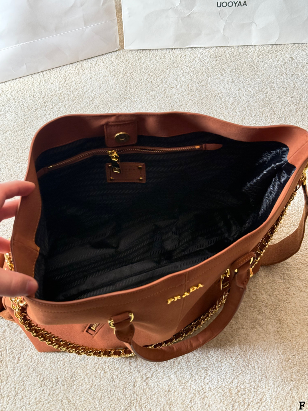 p190 Prada链条托特包 Prada这款棕色链条托特包，采用优质牛皮，手感细腻耐用。金属链条+皮革肩带，手提斜挎都OK，超百搭！正面Logo低调有辦识度，内部空间超大，通勤or短途旅行都能装下日常用品。拉链口袋设计，收纳更方便，实用又时髦，是都市女生的热门选择！ 尺寸 35 33cm