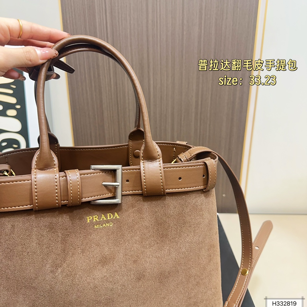 💰235 配盒⚠️尺寸33*23 Prada 普拉达 Buckle翻毛皮手提包 2024春夏系列，采用柔软麂皮，触感细腻，低调哑光质感超有氛围感。标志性金属腰带＋三角徽标，辨识度满分！尺寸适中中，通勤休闲都能轻松驾驱。肩带可拆卸调节，手提斜挎随心切换，实用又时髦。简约大气，时尚爱好者必入！