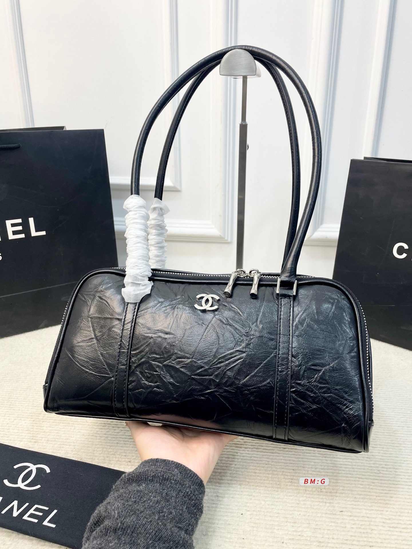 💰225 香奈儿黑色油蜡皮保龄球包，经典弧形设计，油蜡皮自带褶皱纹理，复古又高级✨。正面金属双C Logo超有辨识度，拉链开合更安全。内部空间合理，通勤休闲都能装。手柄弧形，手提肩背都OK，实用又时髦。 尺寸：31*9*16.5