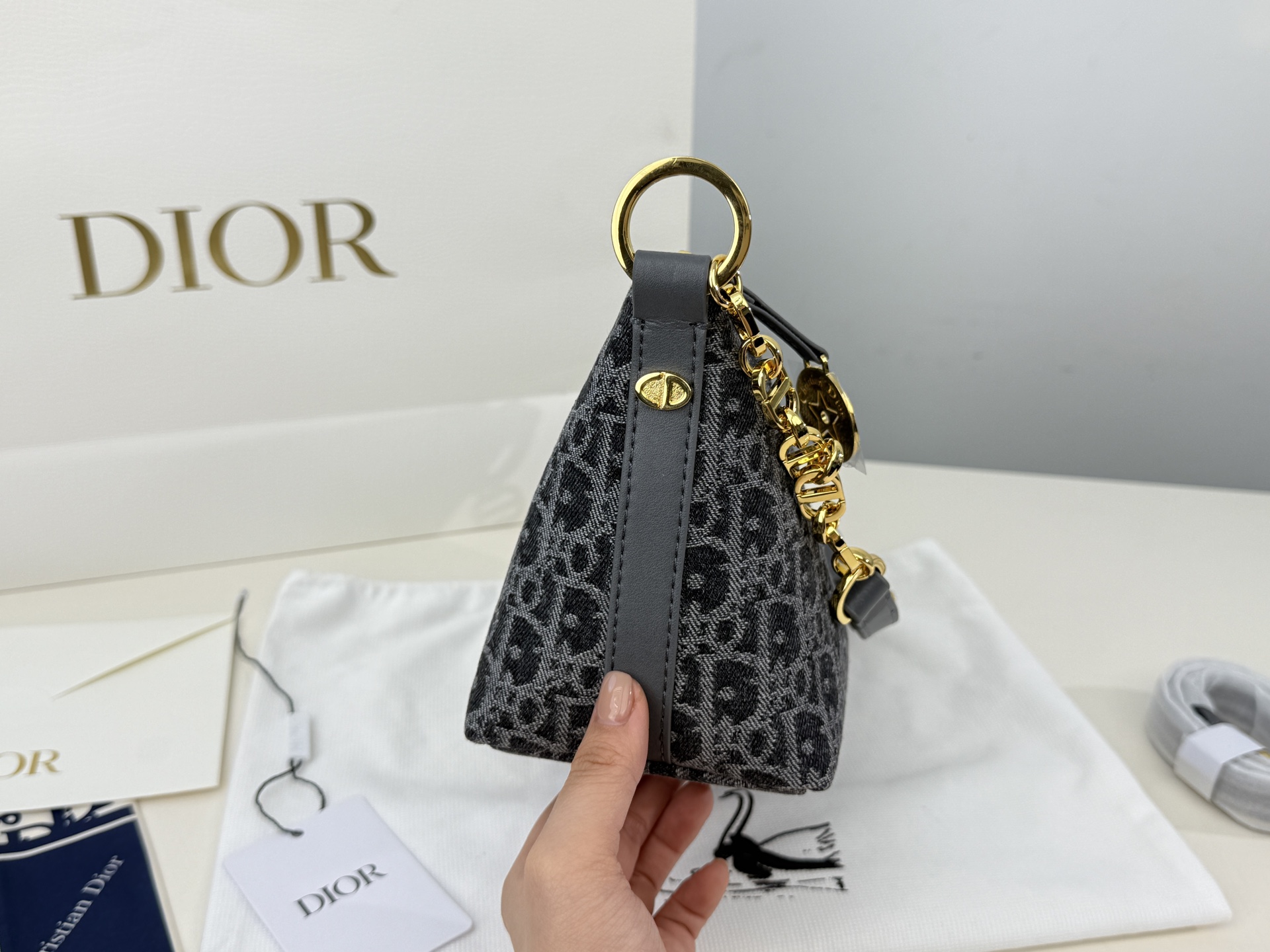 （折叠盒⚠️）p195 迪奥Dior 牛仔链条饭盒（自带延长带） 这款 Diorstar Hobo 链条手袋造型时尚，设计实用。采用蓝色 Denim Dior Oblique 提花面料精心制作，以不规则的石洗效果焕新演绎 Dior 的经典图案，彰显现代魅力，柔软版型搭配宽敞隔层。拉链开合，搭配镌刻以 Christian Dior Paris 标志和 Dior 经典星星标识的圆形饰牌，侧面饰以精致的 CD 铆钉，更显格调。内部带有绒面牛皮革里料，配有卡槽。搭配可调节的 CD 链条肩带，并带有皮革带，提升肩背时的舒适度。 size：22.16cm