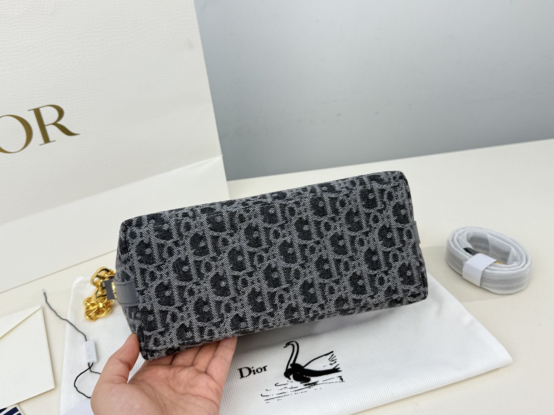 （折叠盒⚠️）p195 迪奥Dior 牛仔链条饭盒（自带延长带） 这款 Diorstar Hobo 链条手袋造型时尚，设计实用。采用蓝色 Denim Dior Oblique 提花面料精心制作，以不规则的石洗效果焕新演绎 Dior 的经典图案，彰显现代魅力，柔软版型搭配宽敞隔层。拉链开合，搭配镌刻以 Christian Dior Paris 标志和 Dior 经典星星标识的圆形饰牌，侧面饰以精致的 CD 铆钉，更显格调。内部带有绒面牛皮革里料，配有卡槽。搭配可调节的 CD 链条肩带，并带有皮革带，提升肩背时的舒适度。 size：22.16cm