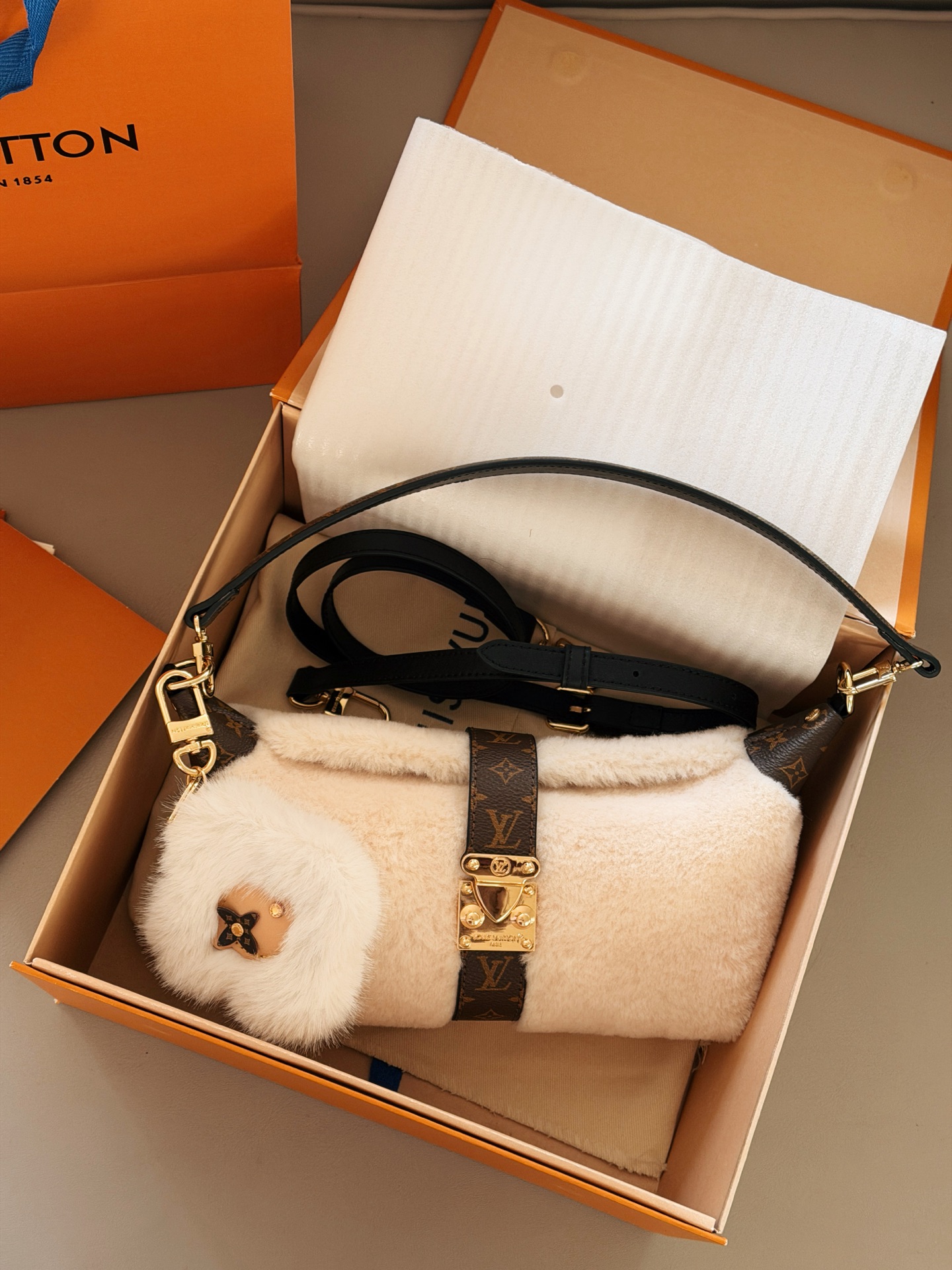 💰 180配盒 赠送挂件哦！ size：21.5*12cm L家 新款MIA饺子包 小小饭盒包拿捏 奶呼呼的毛绒包 摸起来像抱着一团云朵， 老花皮拼接+金属扣设计复古又高级 还有可爱的花朵挂饰加持 冬天背它出门，保暖又吸睛哦！