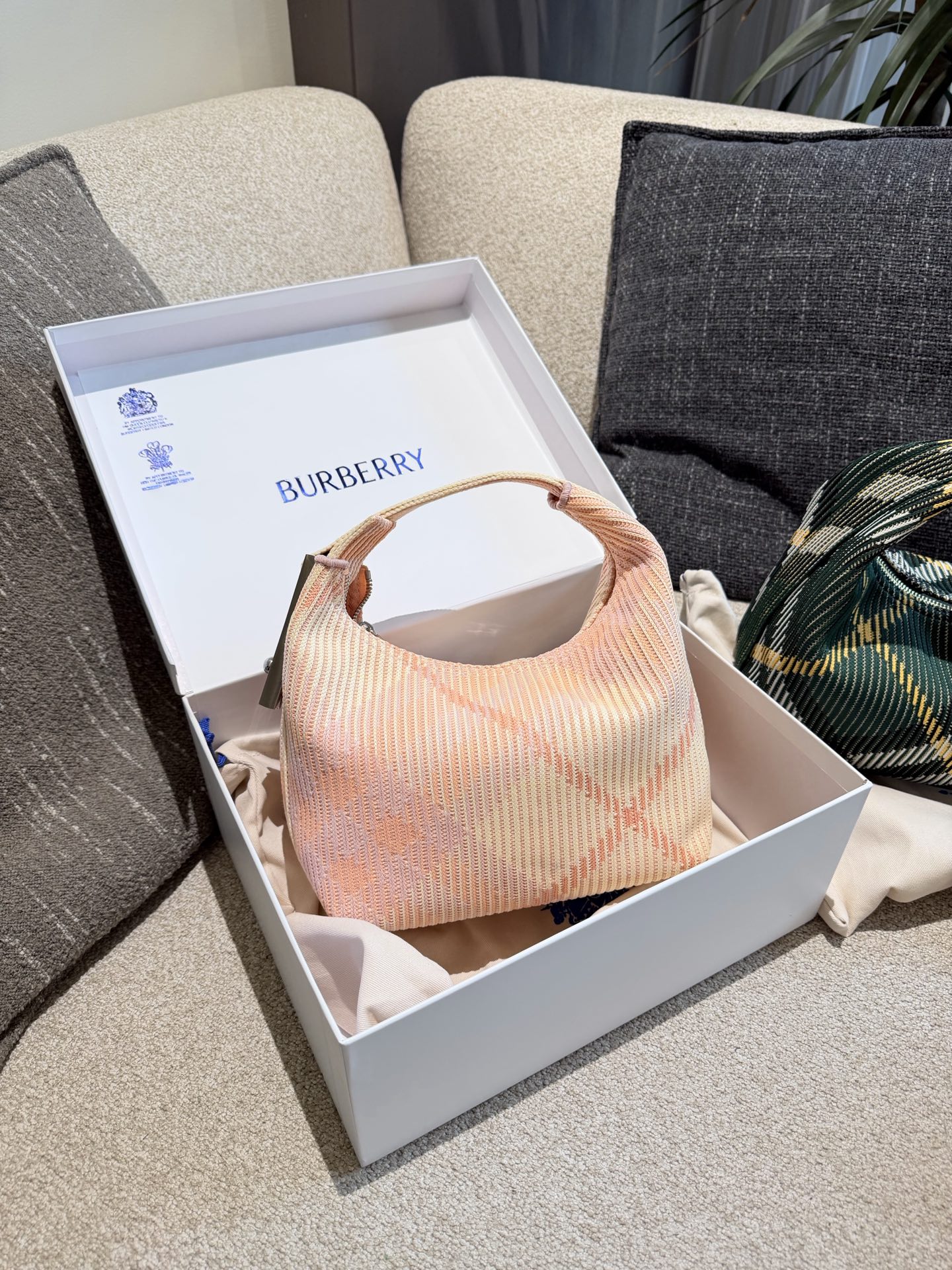 p215 Burberry粉色Peg腋下包 Burberry粉色Peg腋下包，采用柔软编织材质,触感温暖轻盈，春夏穿搭超适合!包身简约，经典格纹+蜜桃粉，清新优雅又百搭+。23x10.5x21.5cm约23x10.5x21.5cm，容量适中，通勤休闲都能hold住。双提手设计，手提肩背都OK，实用又时髦。Peg系列是Burberry经典款，时尚圈超受欢迎，春夏裙装或休闲装都能轻松搭配，日常出街必备!