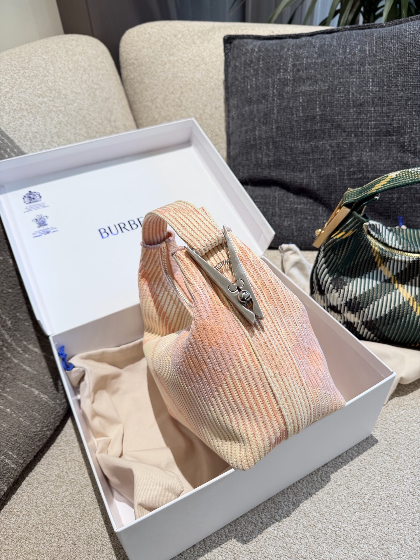 p215 Burberry粉色Peg腋下包 Burberry粉色Peg腋下包，采用柔软编织材质,触感温暖轻盈，春夏穿搭超适合!包身简约，经典格纹+蜜桃粉，清新优雅又百搭+。23x10.5x21.5cm约23x10.5x21.5cm，容量适中，通勤休闲都能hold住。双提手设计，手提肩背都OK，实用又时髦。Peg系列是Burberry经典款，时尚圈超受欢迎，春夏裙装或休闲装都能轻松搭配，日常出街必备!