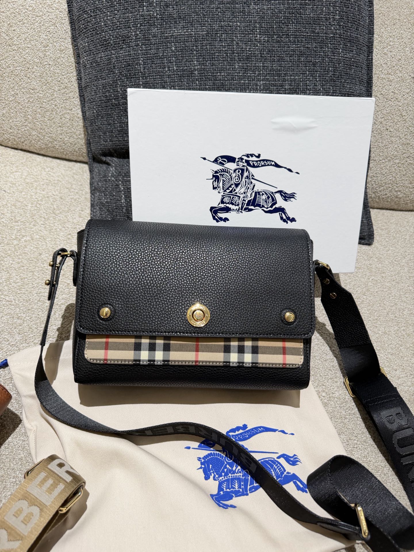 Burberry Note邮差包p165 Burberry Note邮差包，荔枝纹牛皮+经典格纹拼接，低 调又高级!25x17x8cm25x17x8cm，容量超能装，iPad、 雨伞都能放，通勤日常都OK++。宽肩带可调节，减压又百搭,休闲西装都能配。包盖吸扣设计，开合方便，内部空间合理，实用性满分!荔枝纹耐磨耐用，日常通勤、旅行都很 适合，是Burberry经典款，真的很推荐入手!